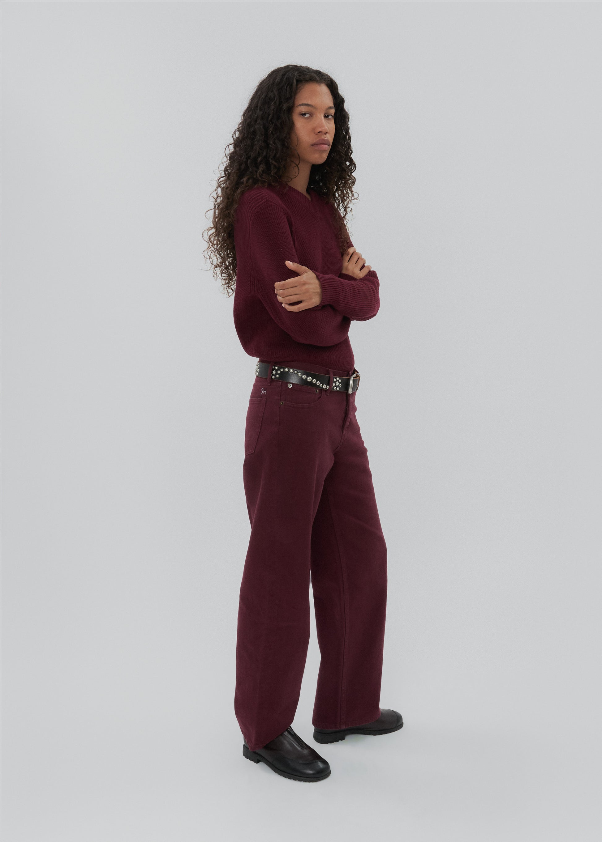 Person wearing a burgundy outfit with a belt on a white background