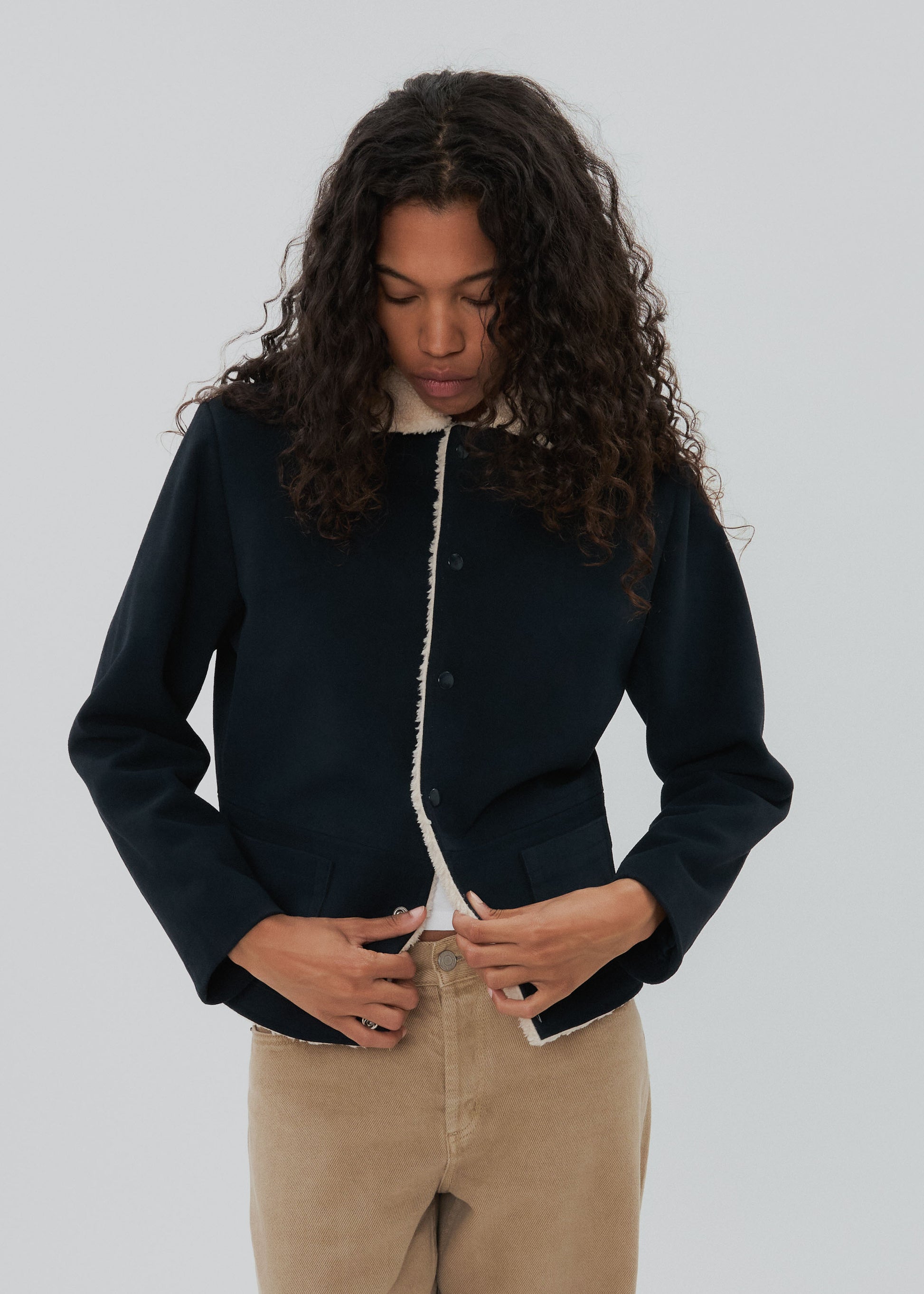 Person wearing a dark blue jacket with white trim against a plain background