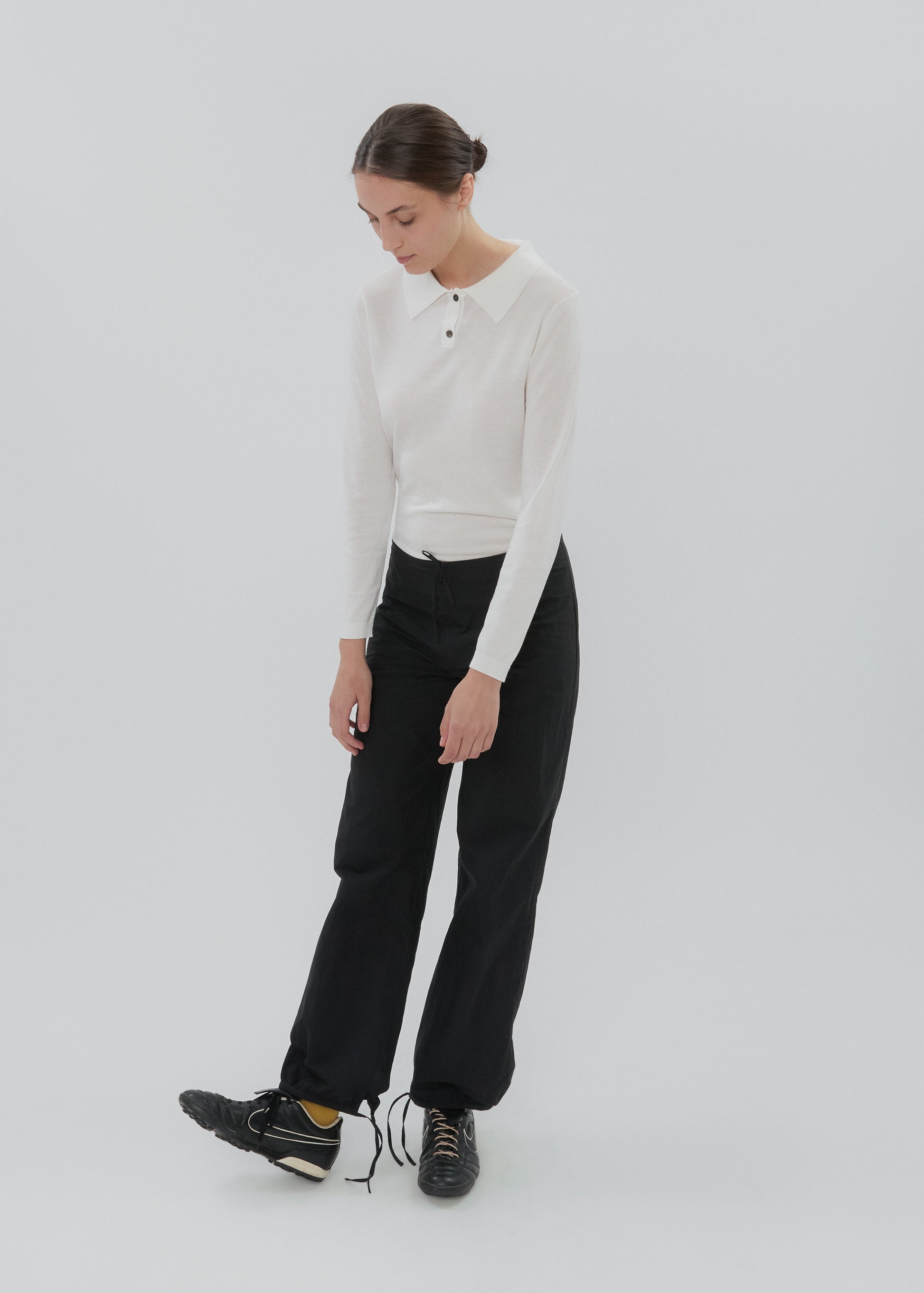 Person wearing a white long-sleeve shirt and black pants on a light gray background