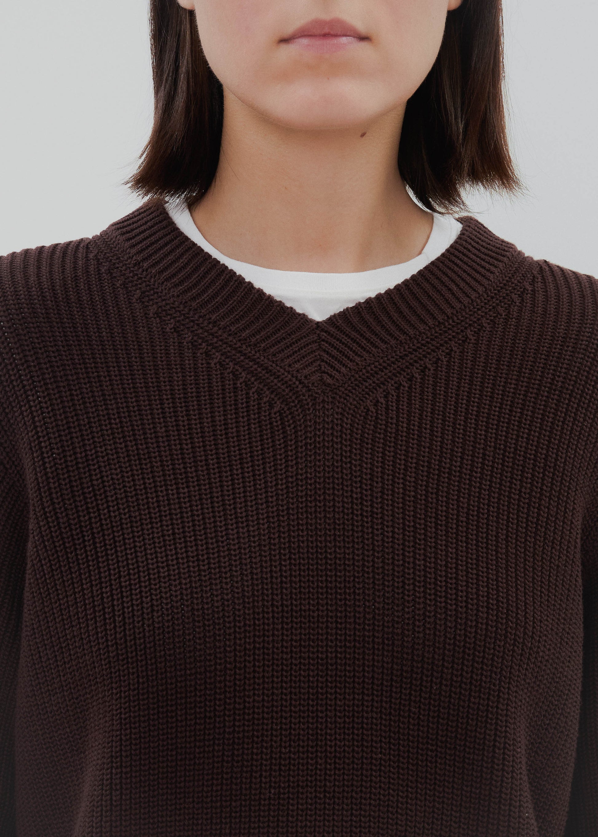 Person wearing a brown sweater with a plain background