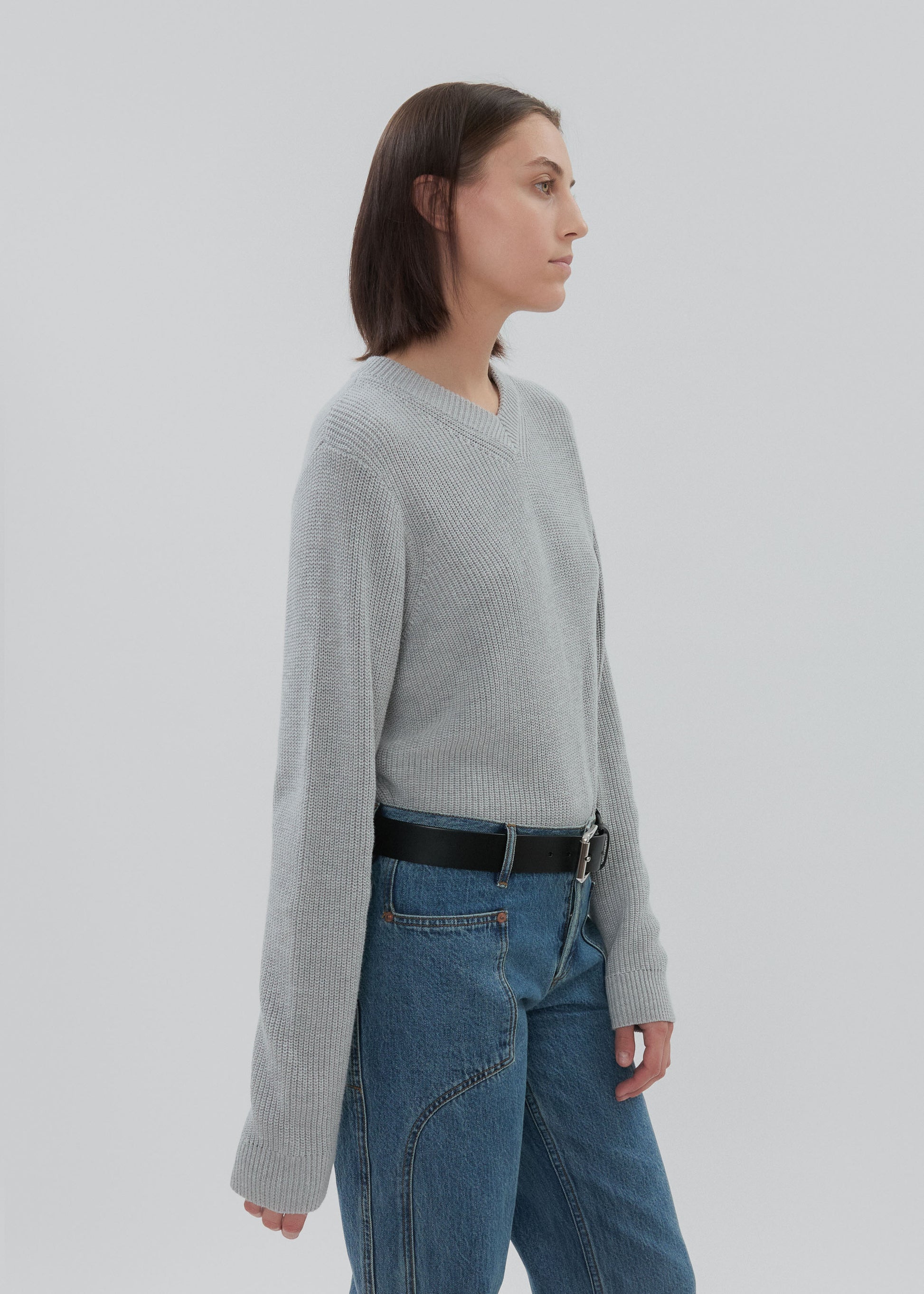 Person wearing a gray sweater and blue jeans on a plain background