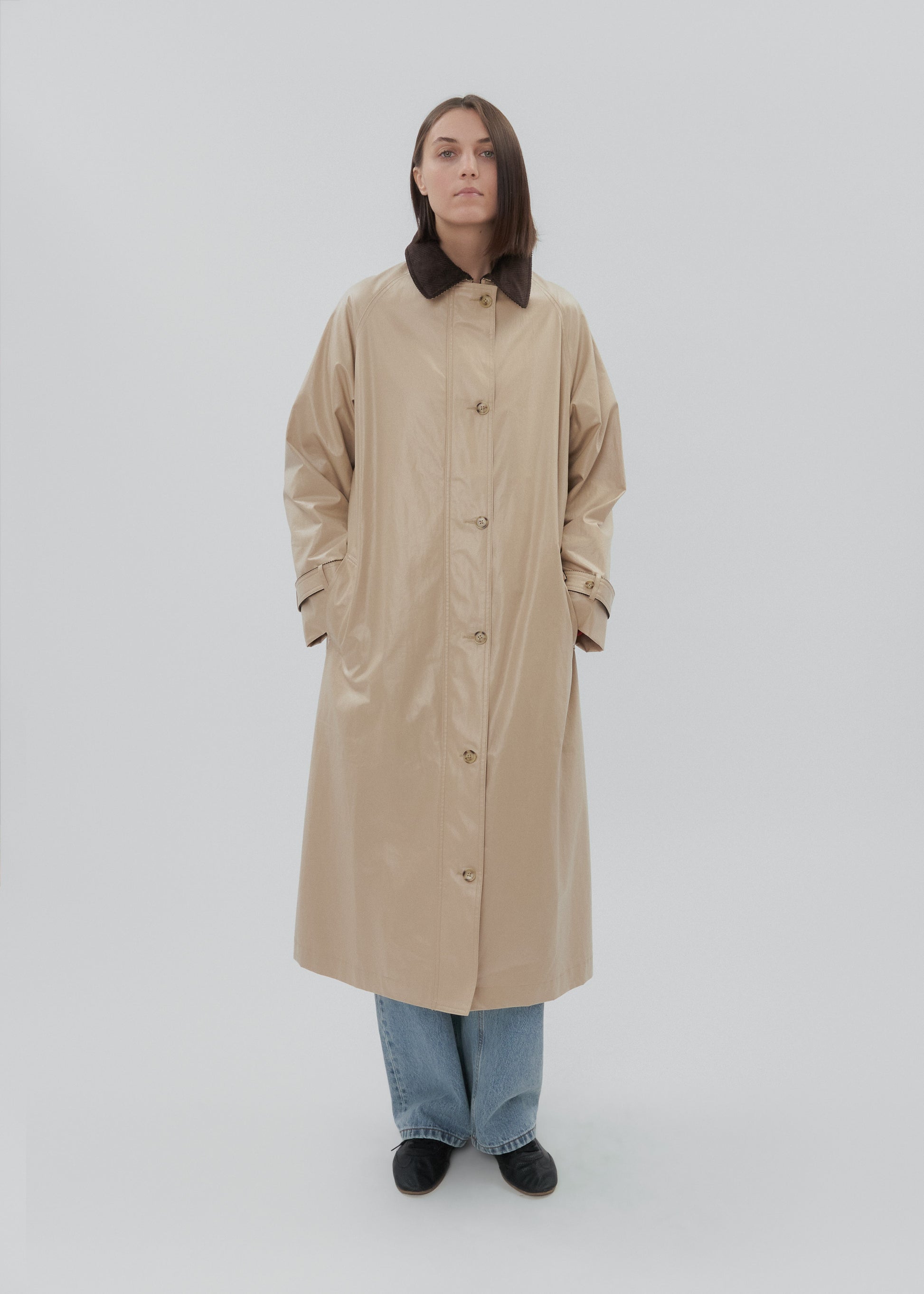 Person wearing a beige trench coat on a white background