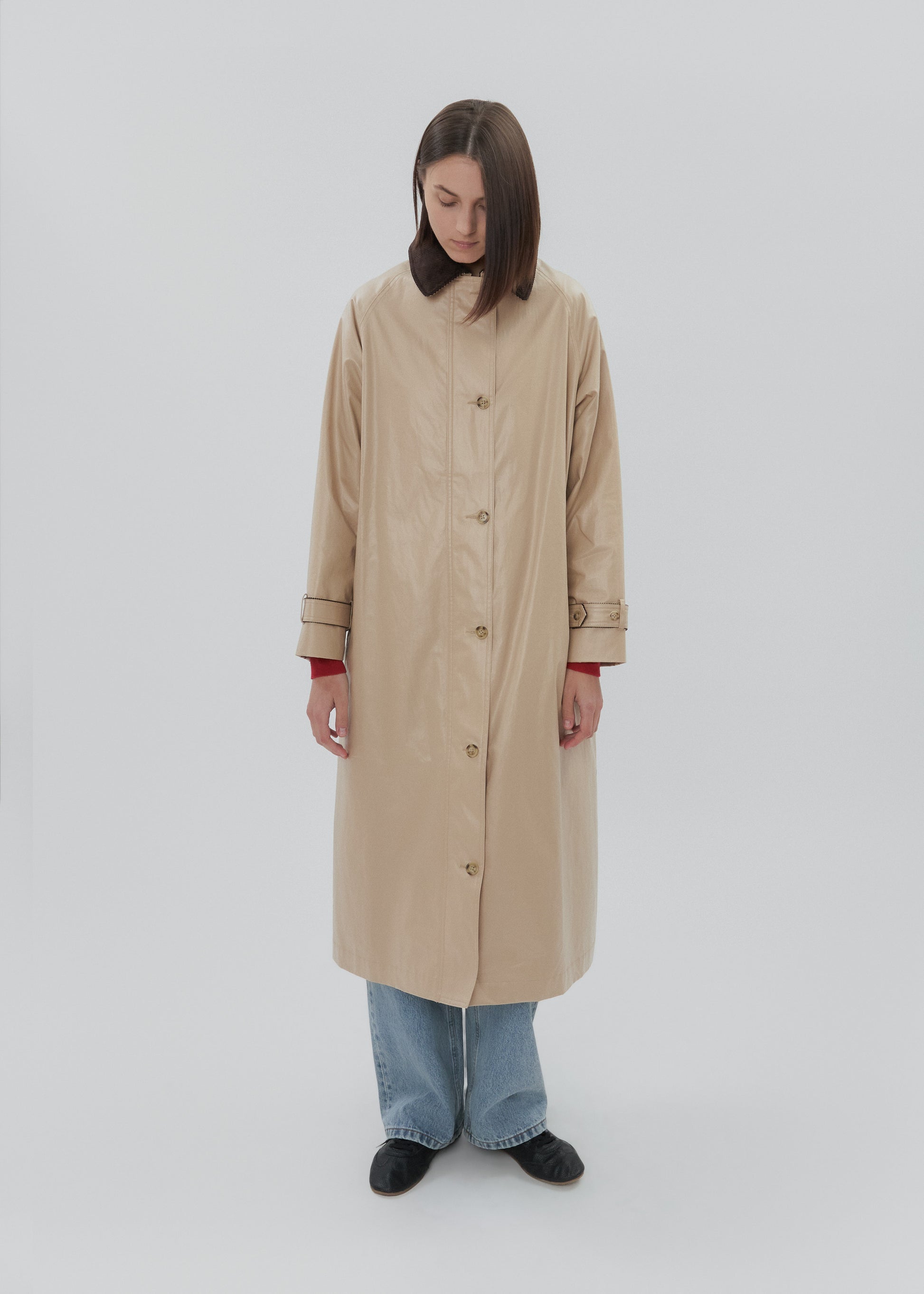 Person wearing a beige trench coat on a white background