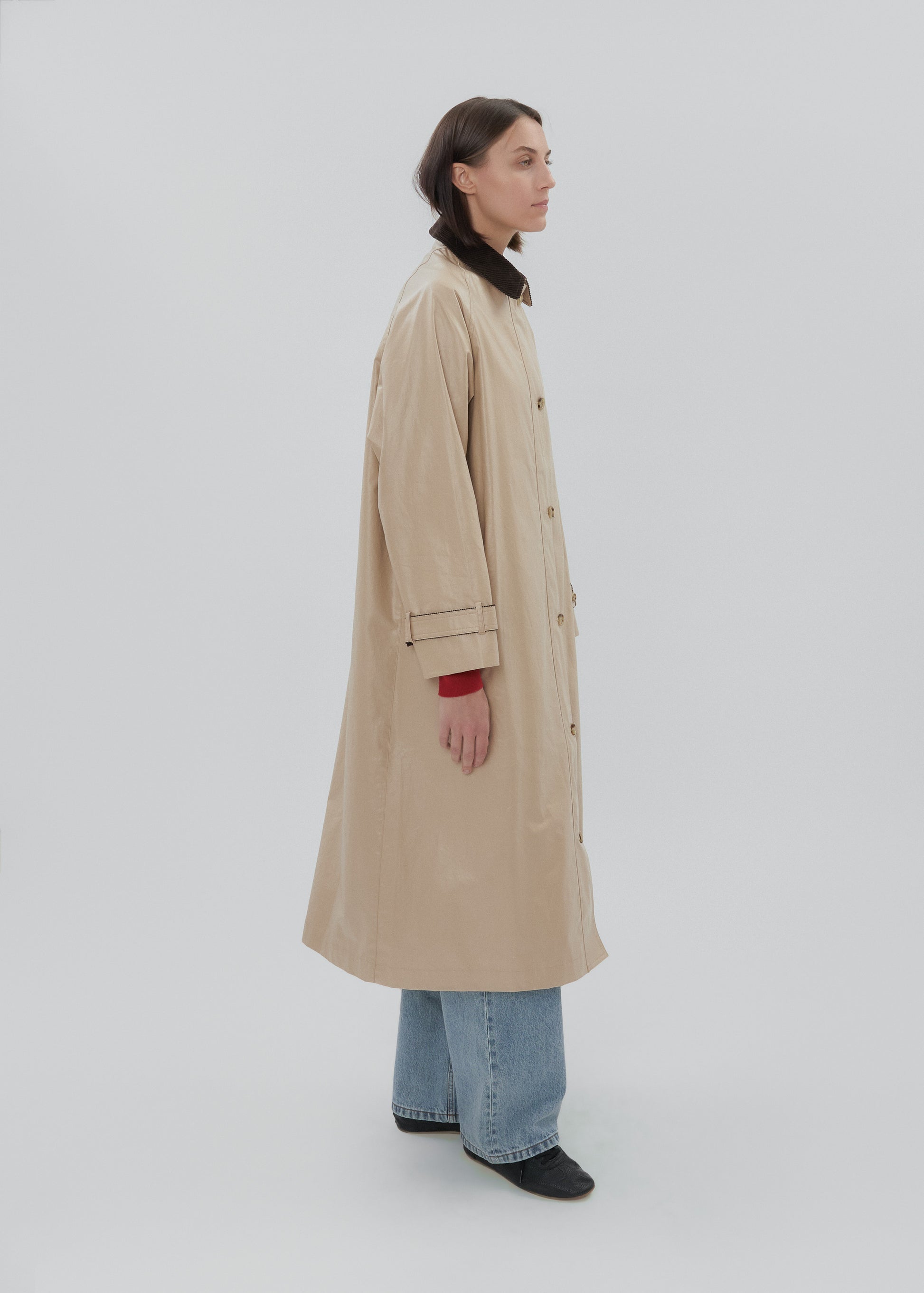 Person wearing a beige trench coat on a white background