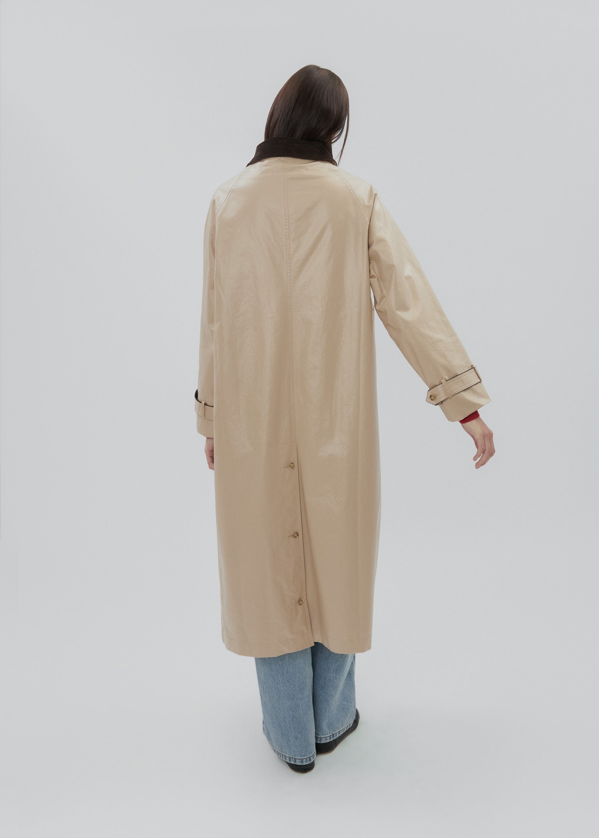 Person wearing a beige trench coat on a white background