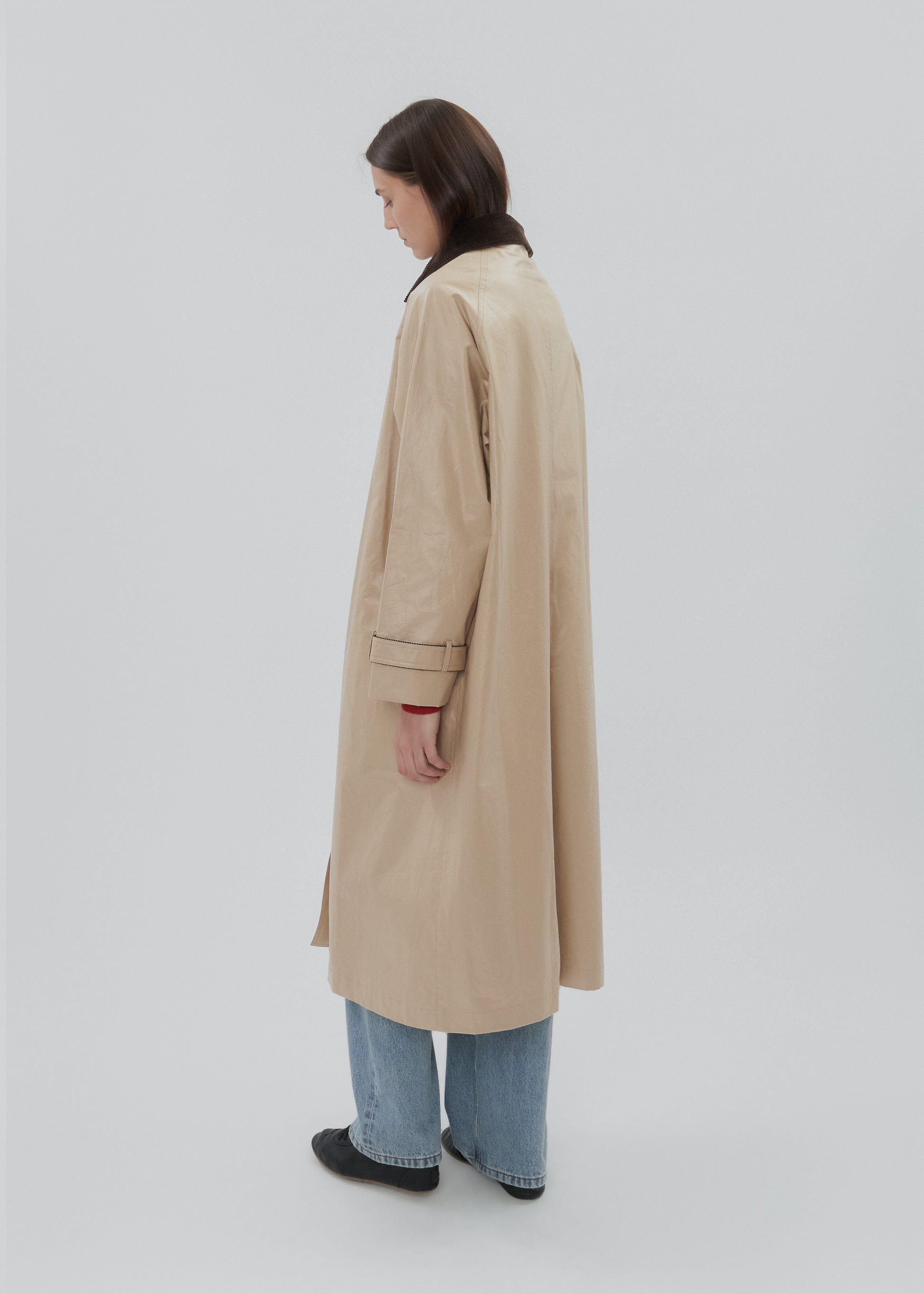 Person wearing a beige trench coat on a white background
