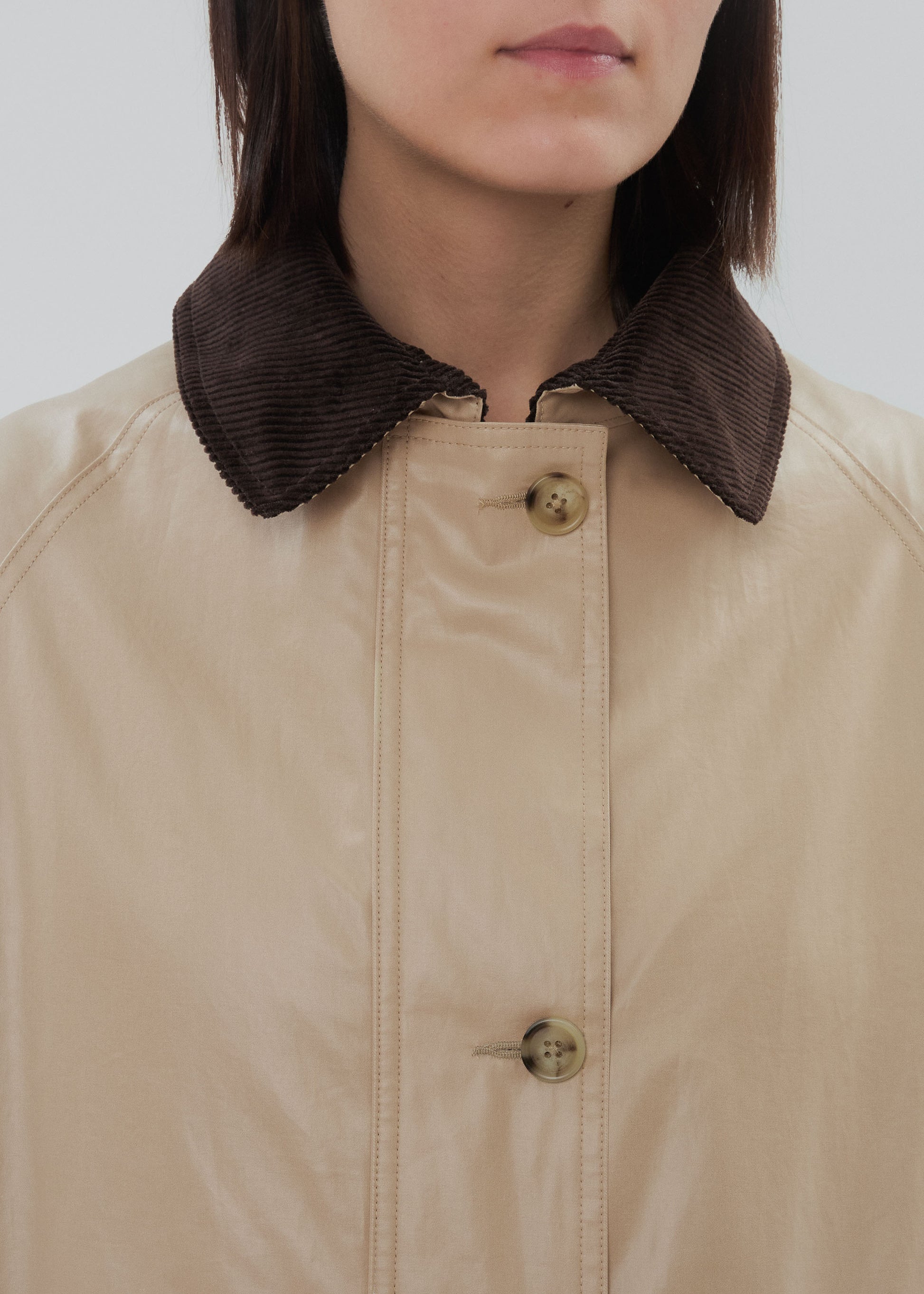 Close-up of a person wearing a beige jacket with a brown corduroy collar.