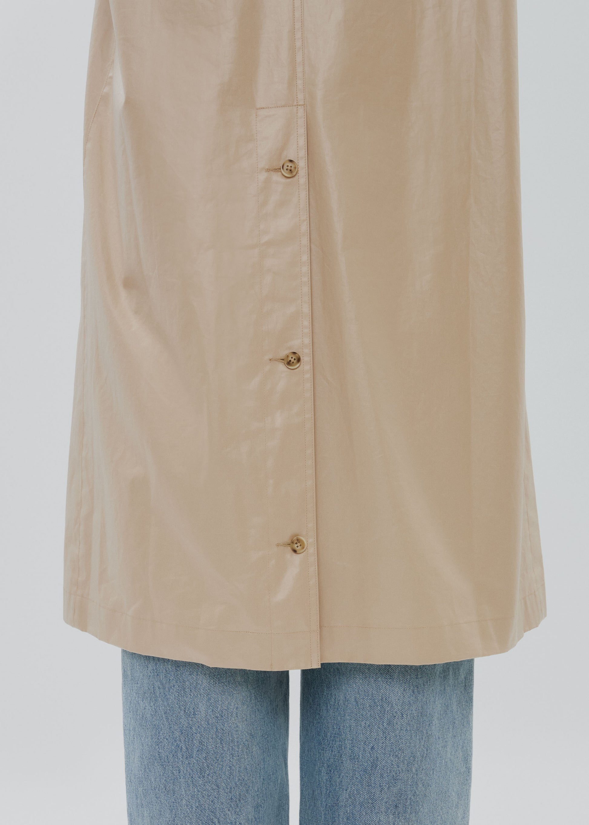 Beige raincoat with gold buttons on a white background