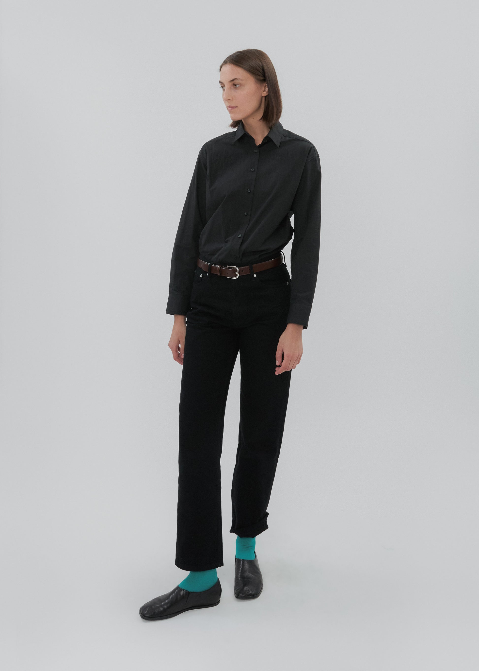Person wearing a black shirt and pants with a belt on a white background