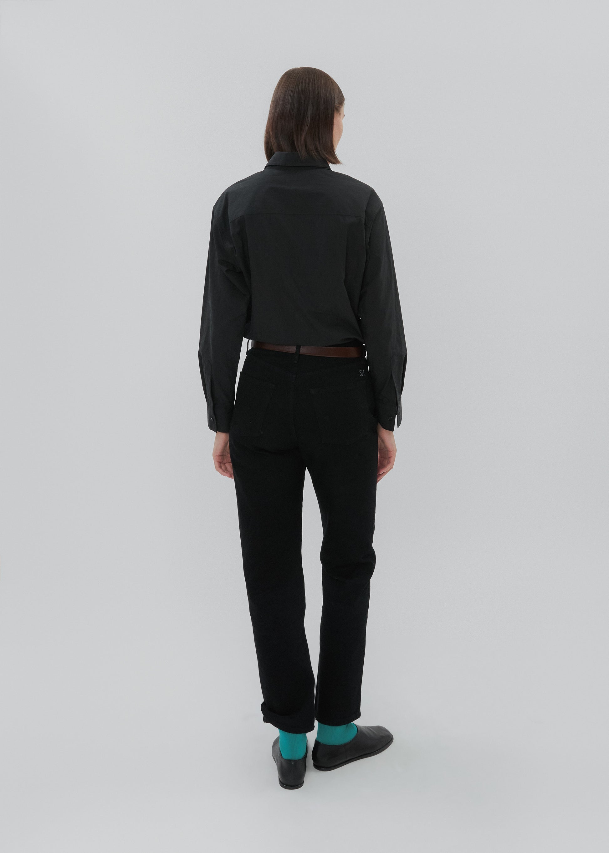Person wearing a black outfit with turquoise socks on a white background