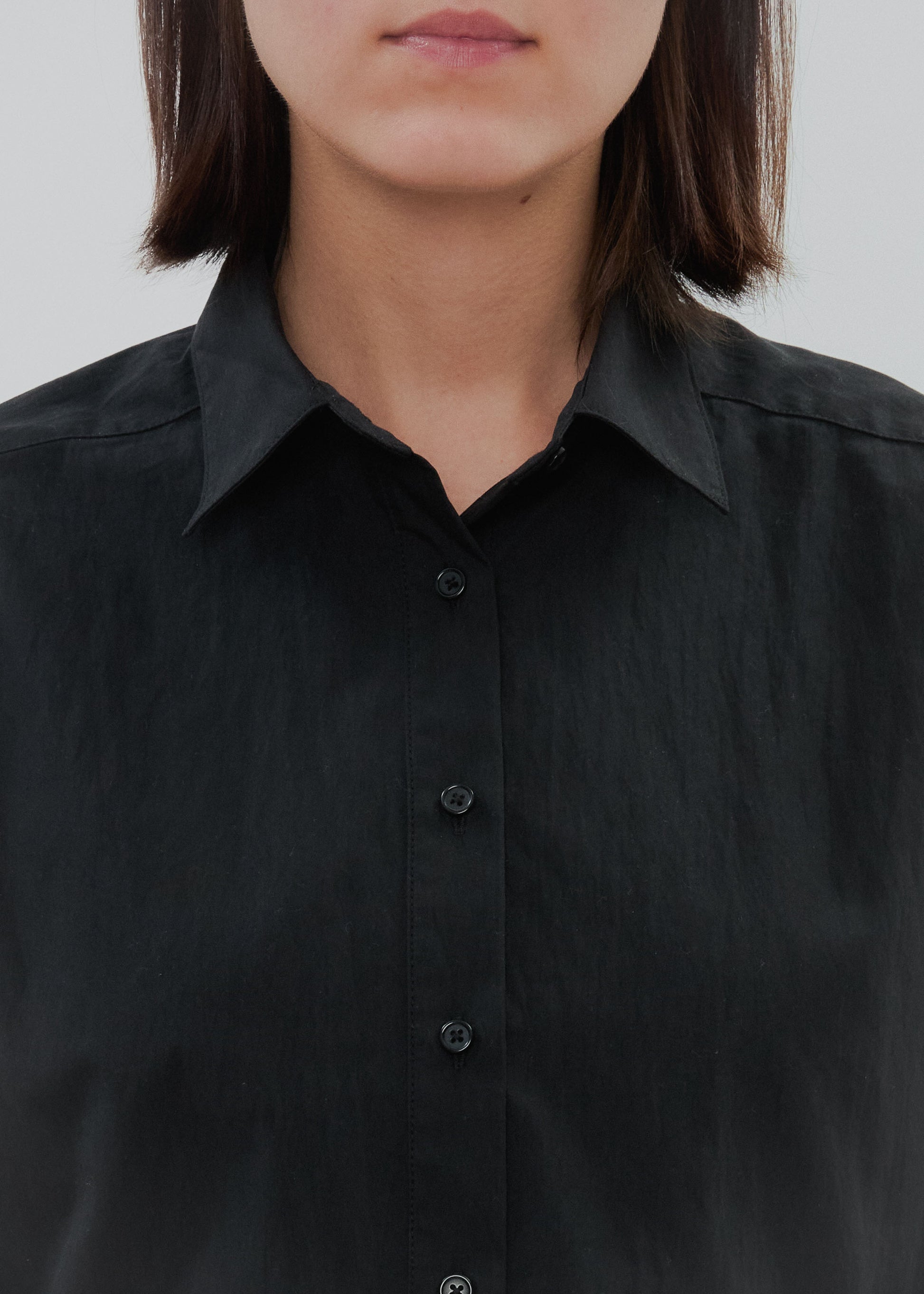 Person wearing a black button-up shirt against a plain background