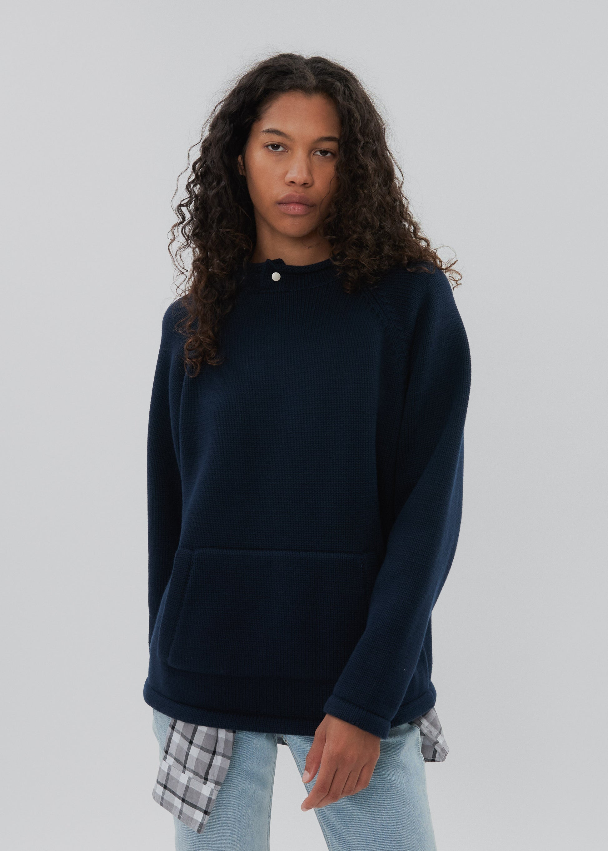 Person wearing a navy blue sweater with a plain background