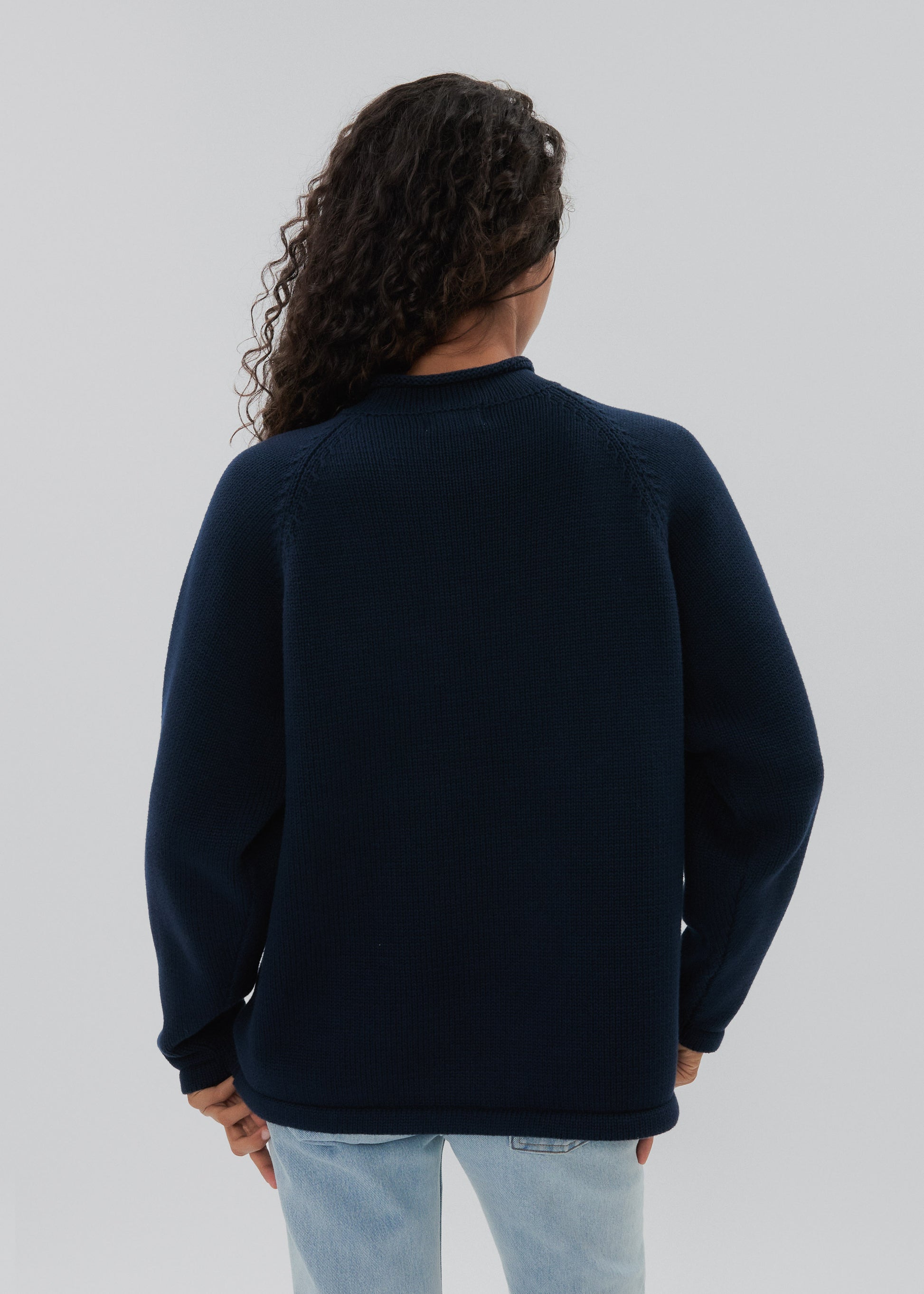 Person wearing a navy blue sweater on a light gray background