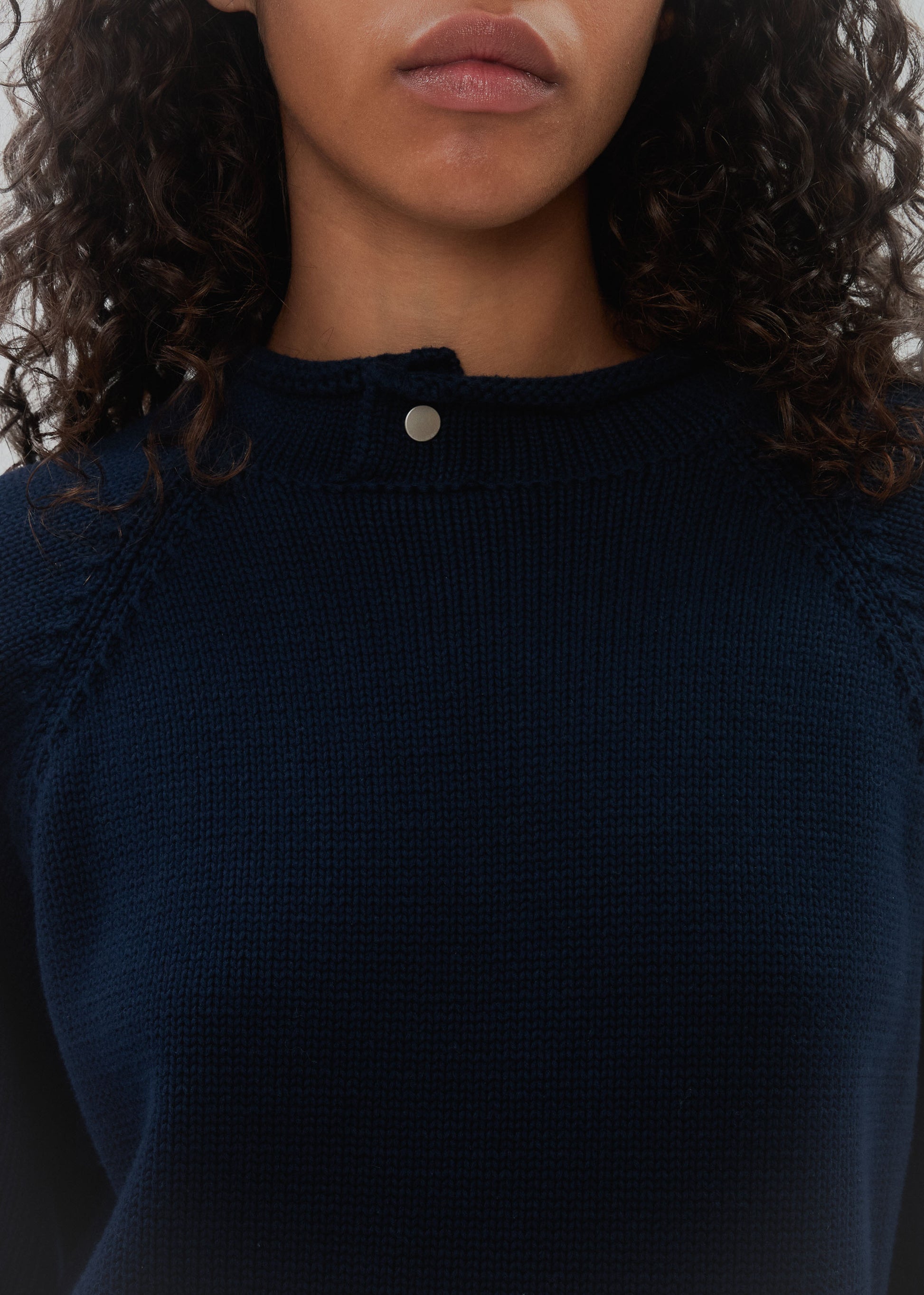 Navy blue top with a close-up of the neckline on a plain background