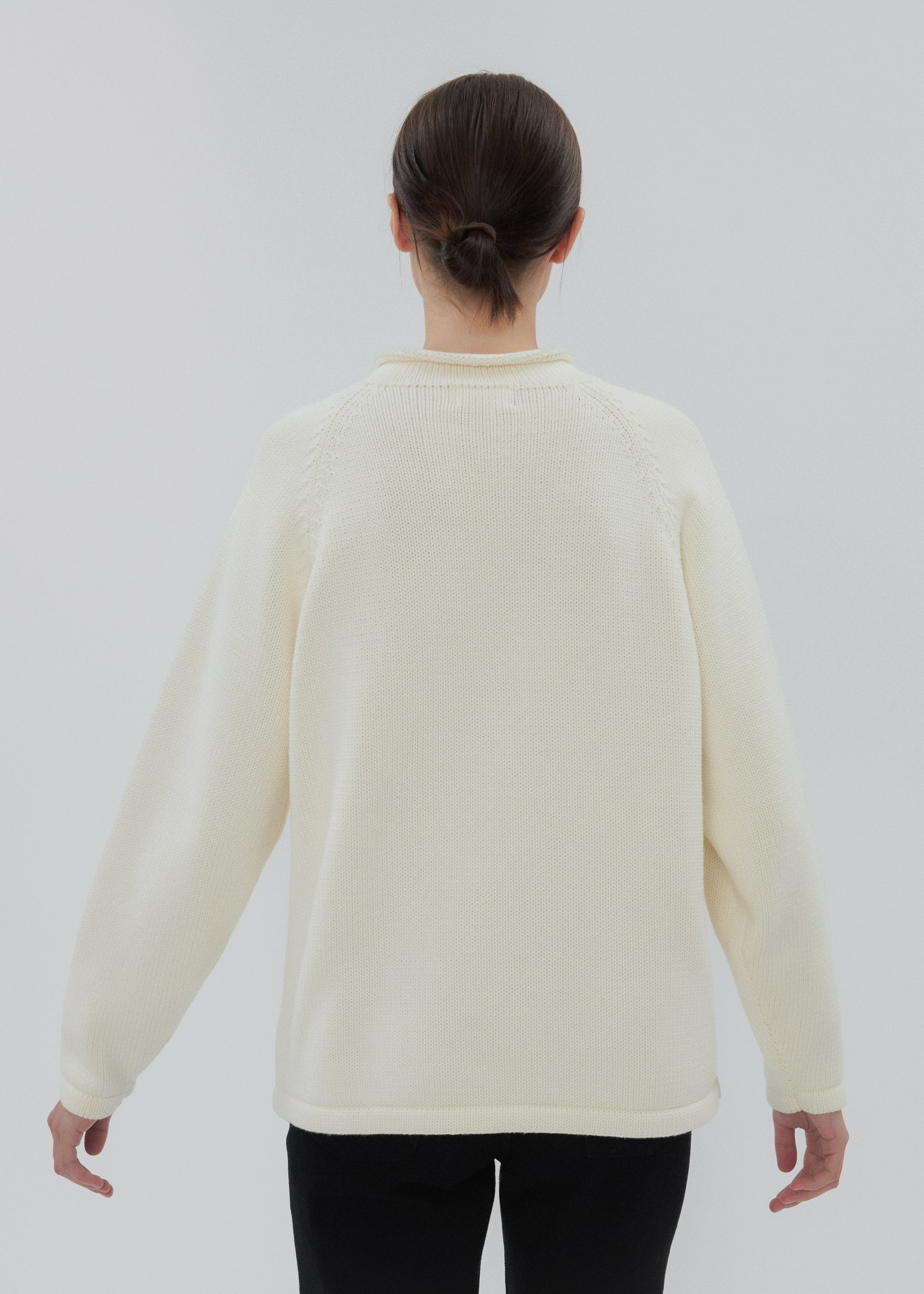 Person wearing a cream sweater on a white background