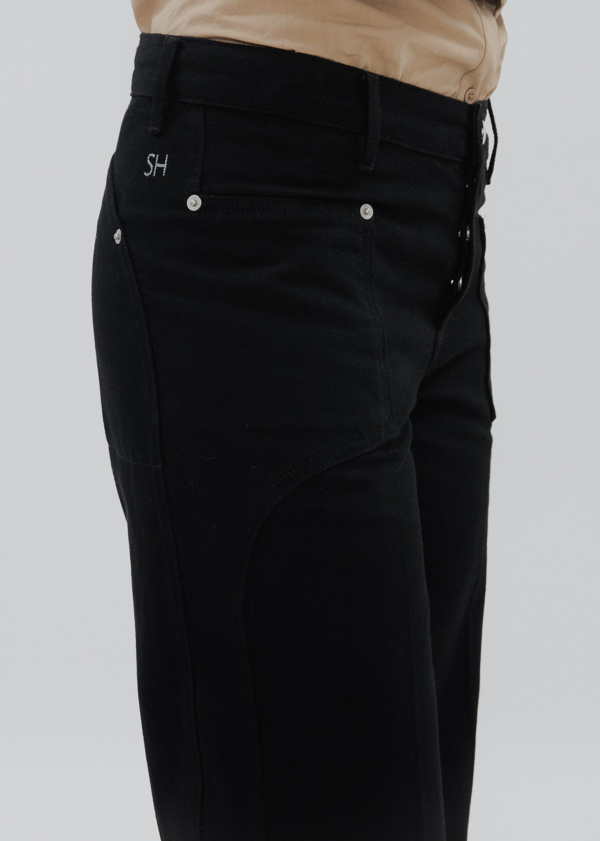 Black pants with silver buttons on a light gray background