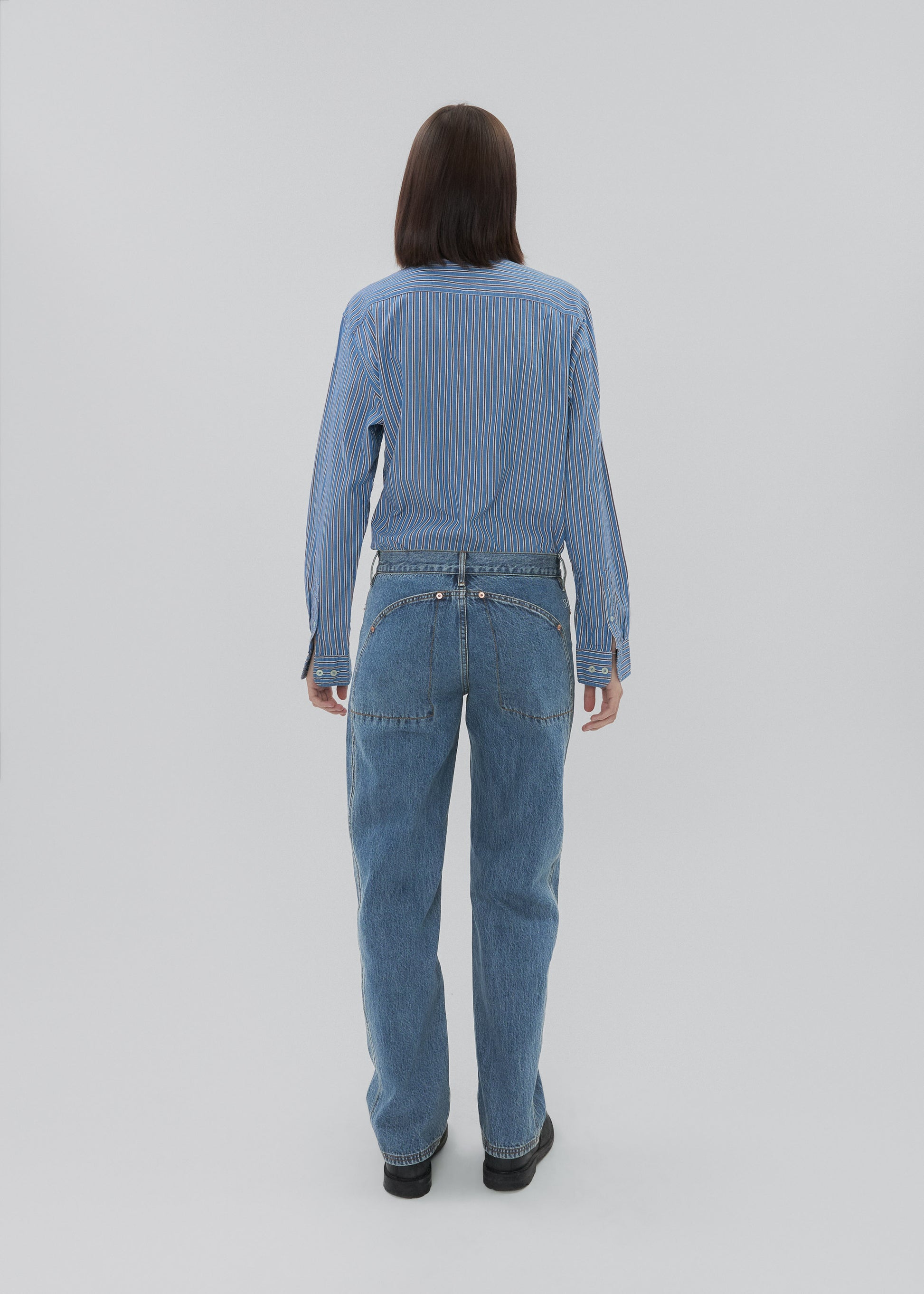 Person wearing a blue denim jumpsuit on a white background