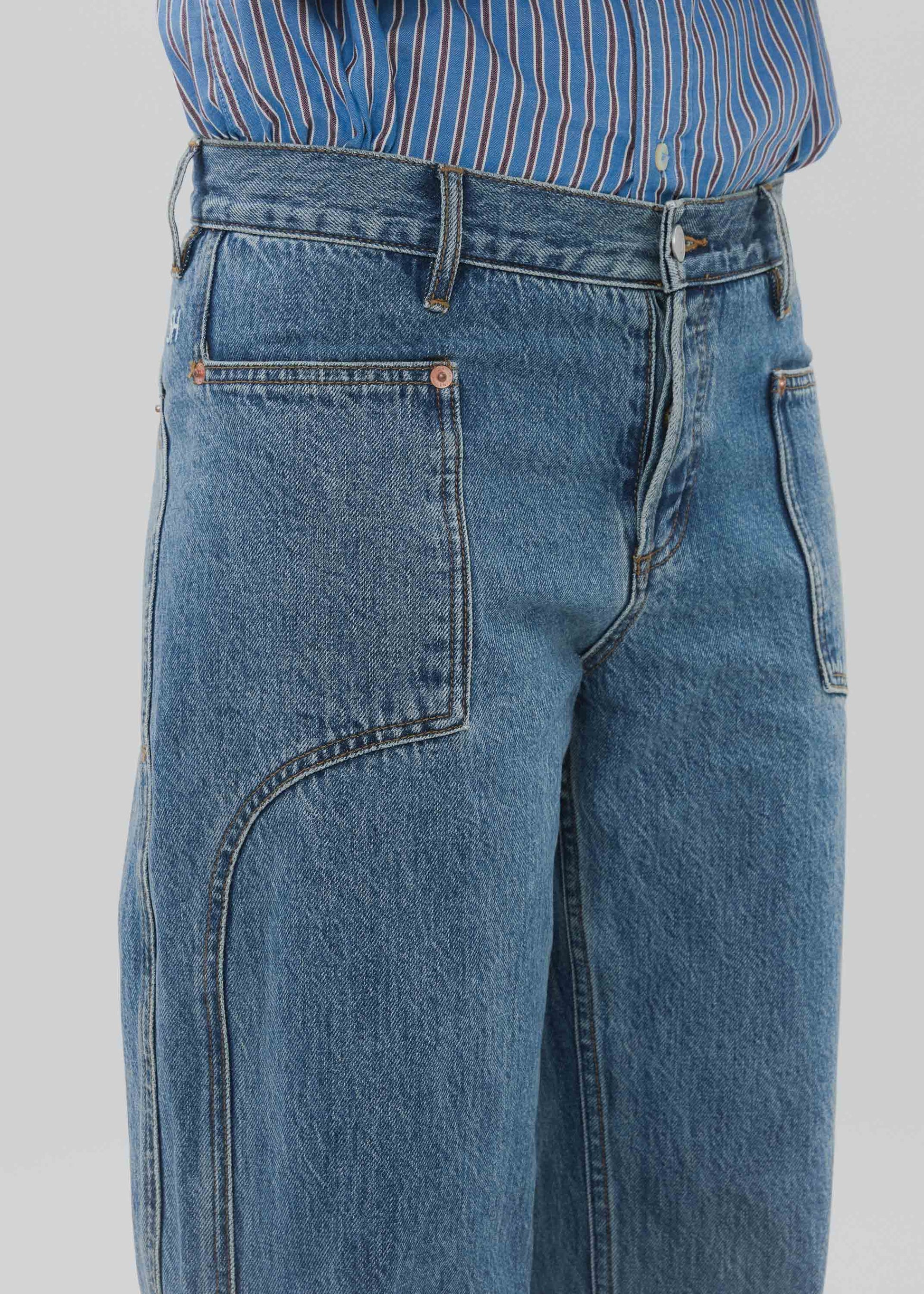 Blue jeans worn with a striped shirt on a plain background