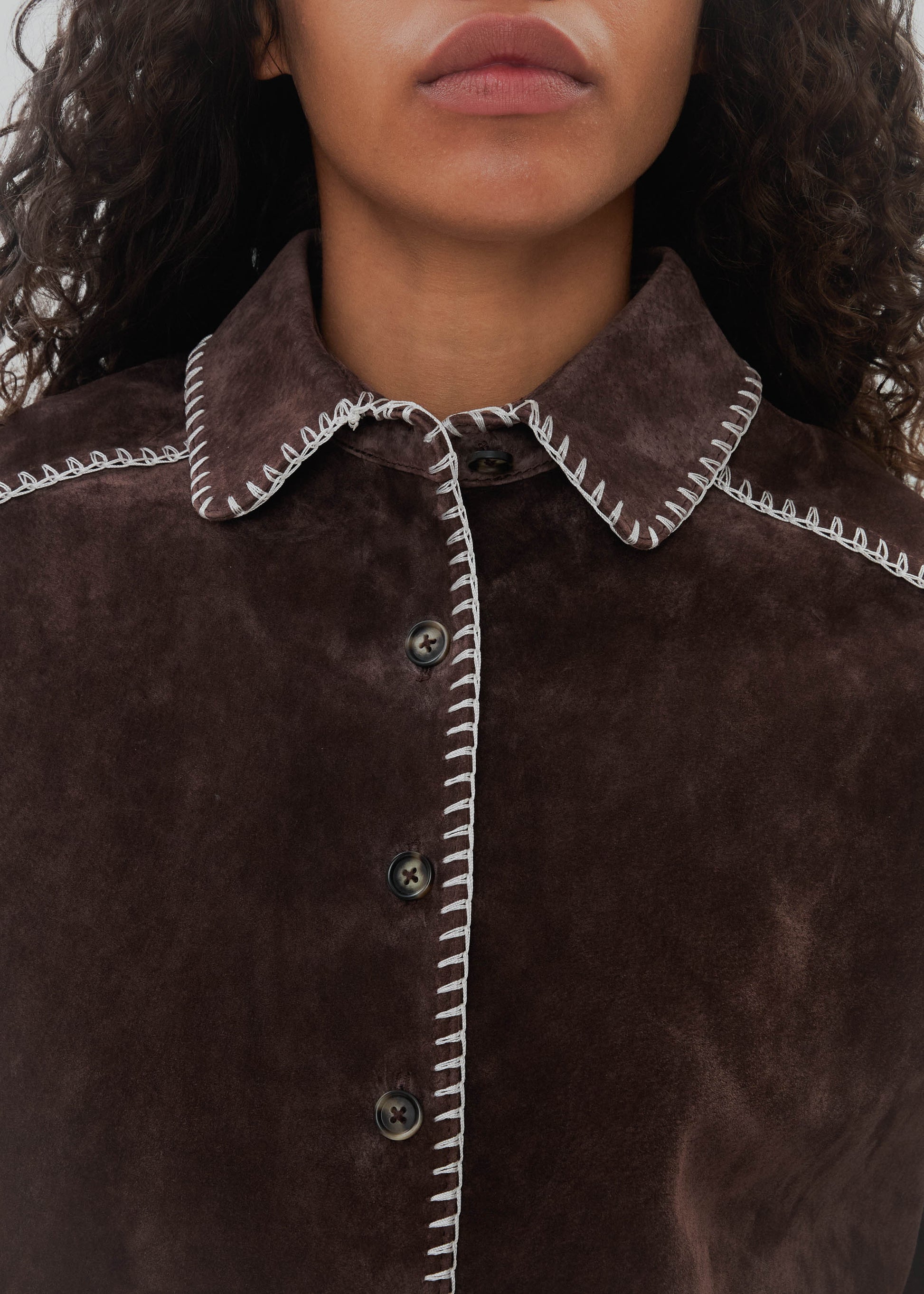 Close-up of a brown textured garment with white stitching details.