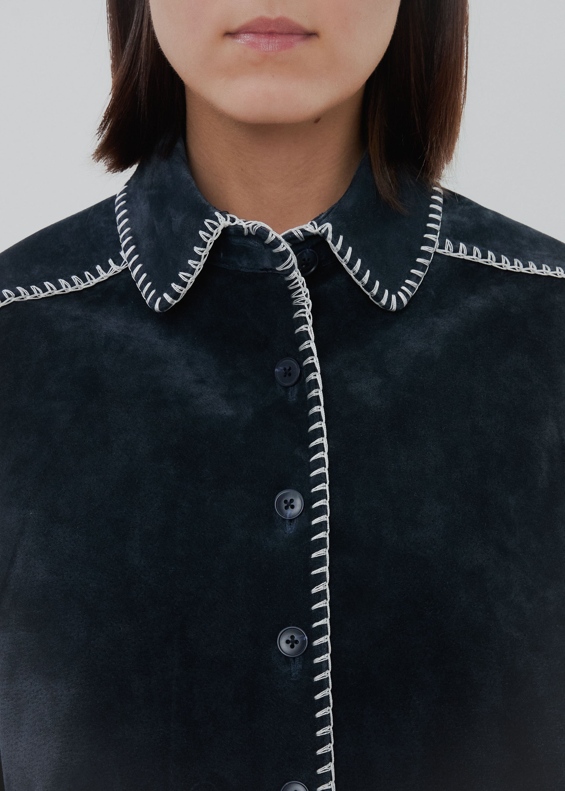 Dark blue shirt with white trim on a plain background