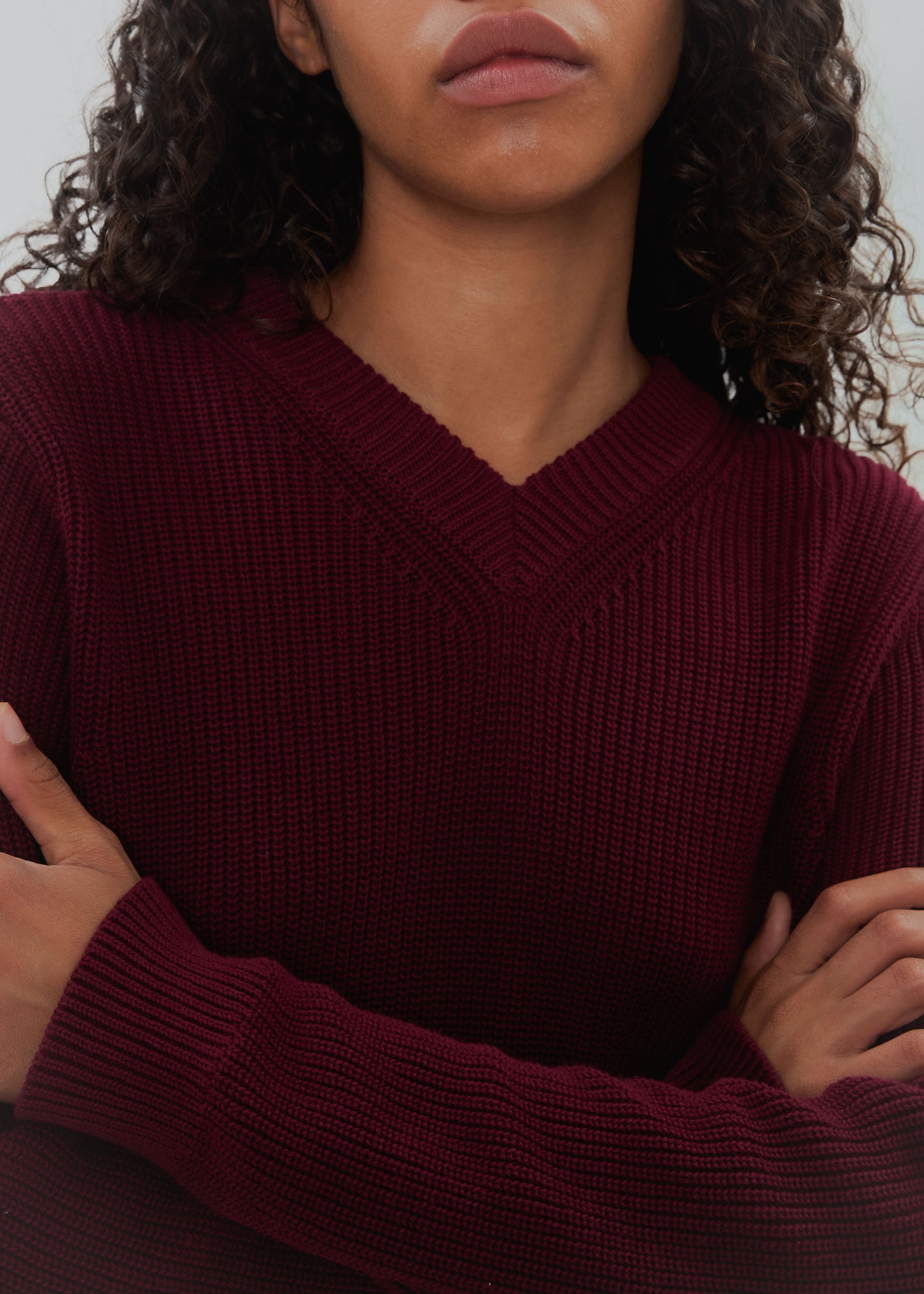 Person wearing a burgundy sweater with arms crossed