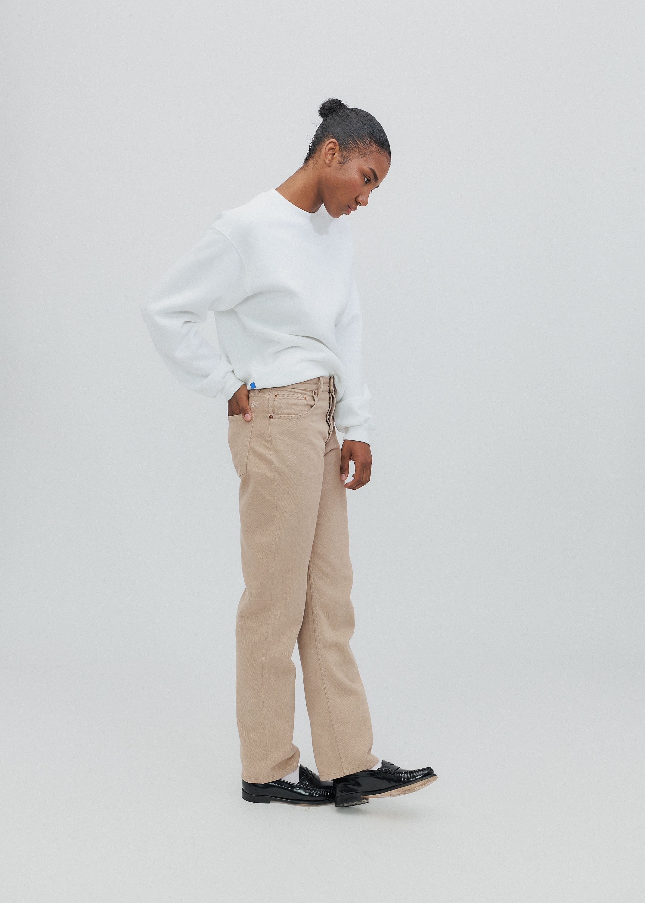 Person wearing a white sweater and beige pants on a light gray background