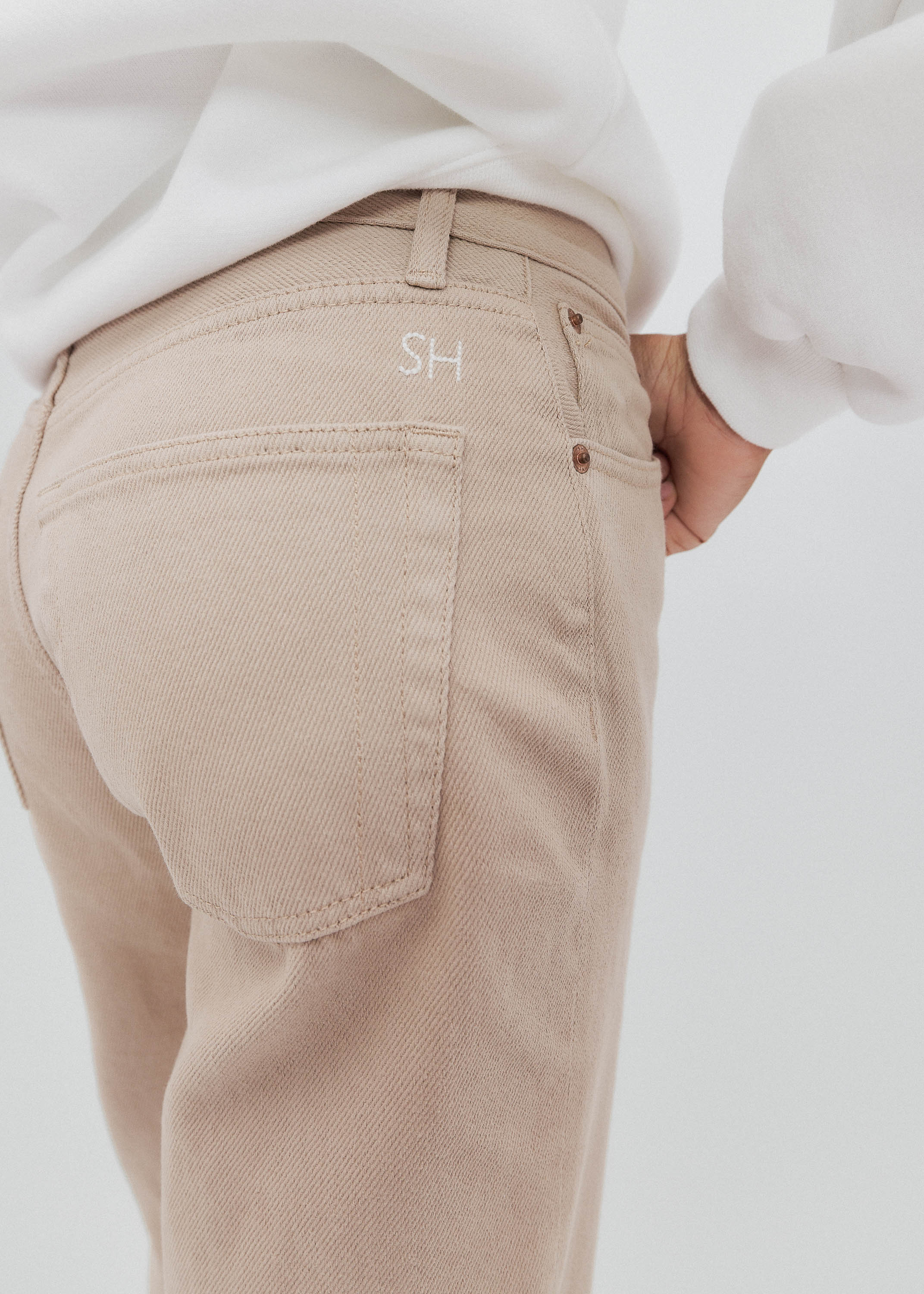 Beige pants with a brand logo on a white background