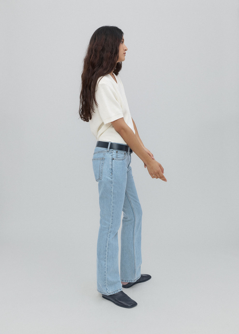 Person wearing light blue jeans and a white shirt on a plain background