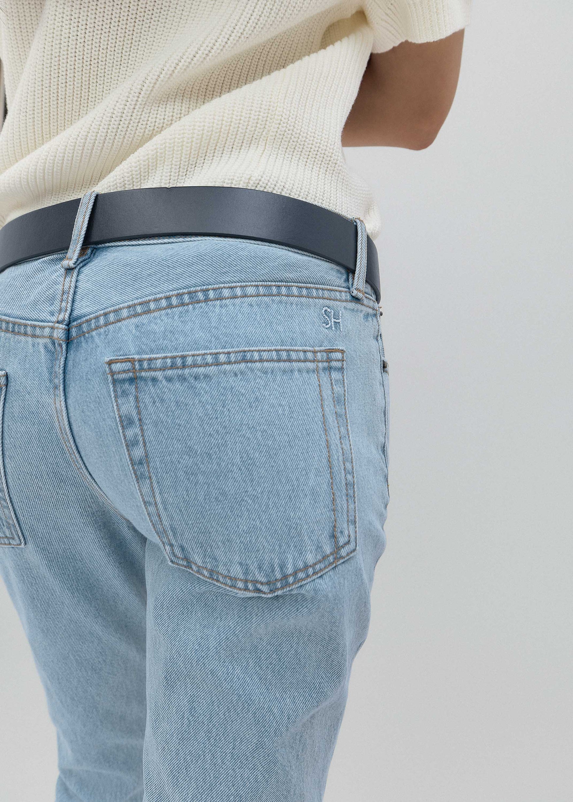 Light blue jeans with a dark belt on a plain background