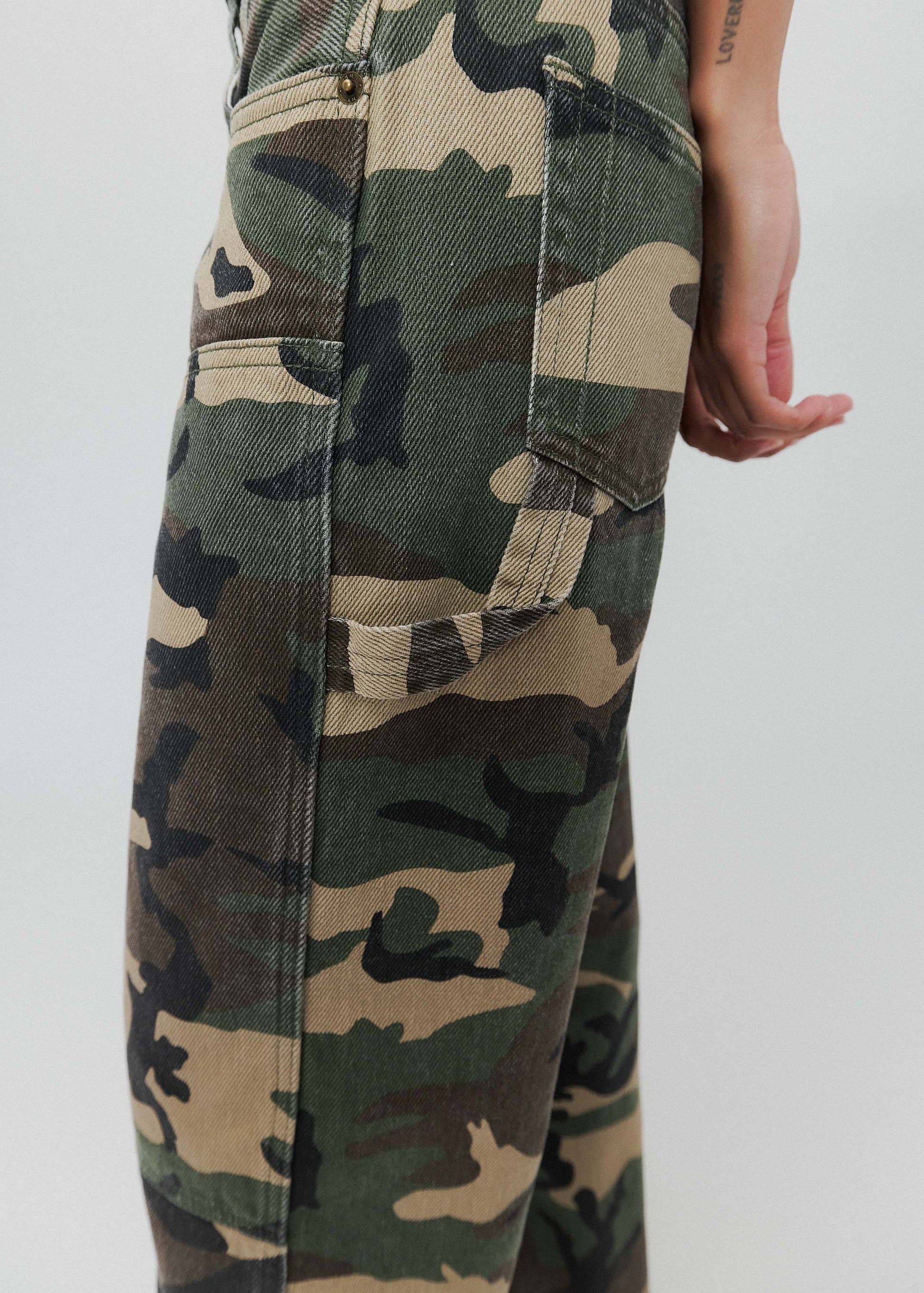 Person wearing camouflage pants and a black shirt on a white background