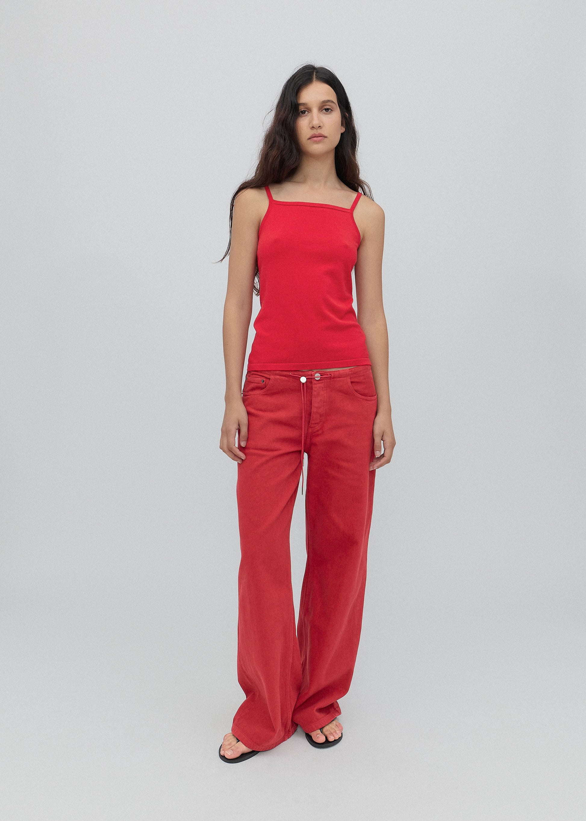 Woman wearing a red sleeveless top and red pants on a light gray background