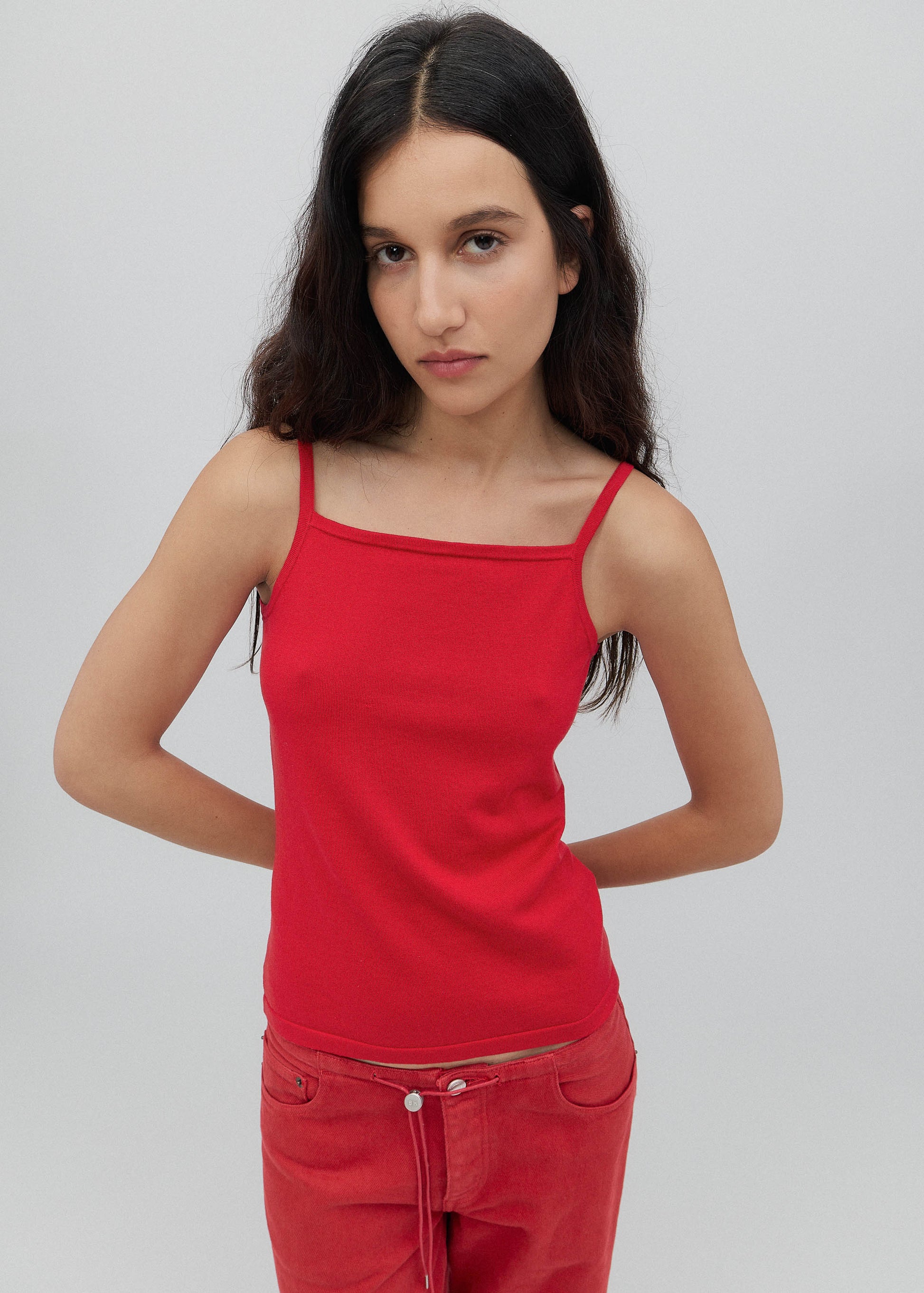 Woman wearing a red tank top and red pants against a gray background