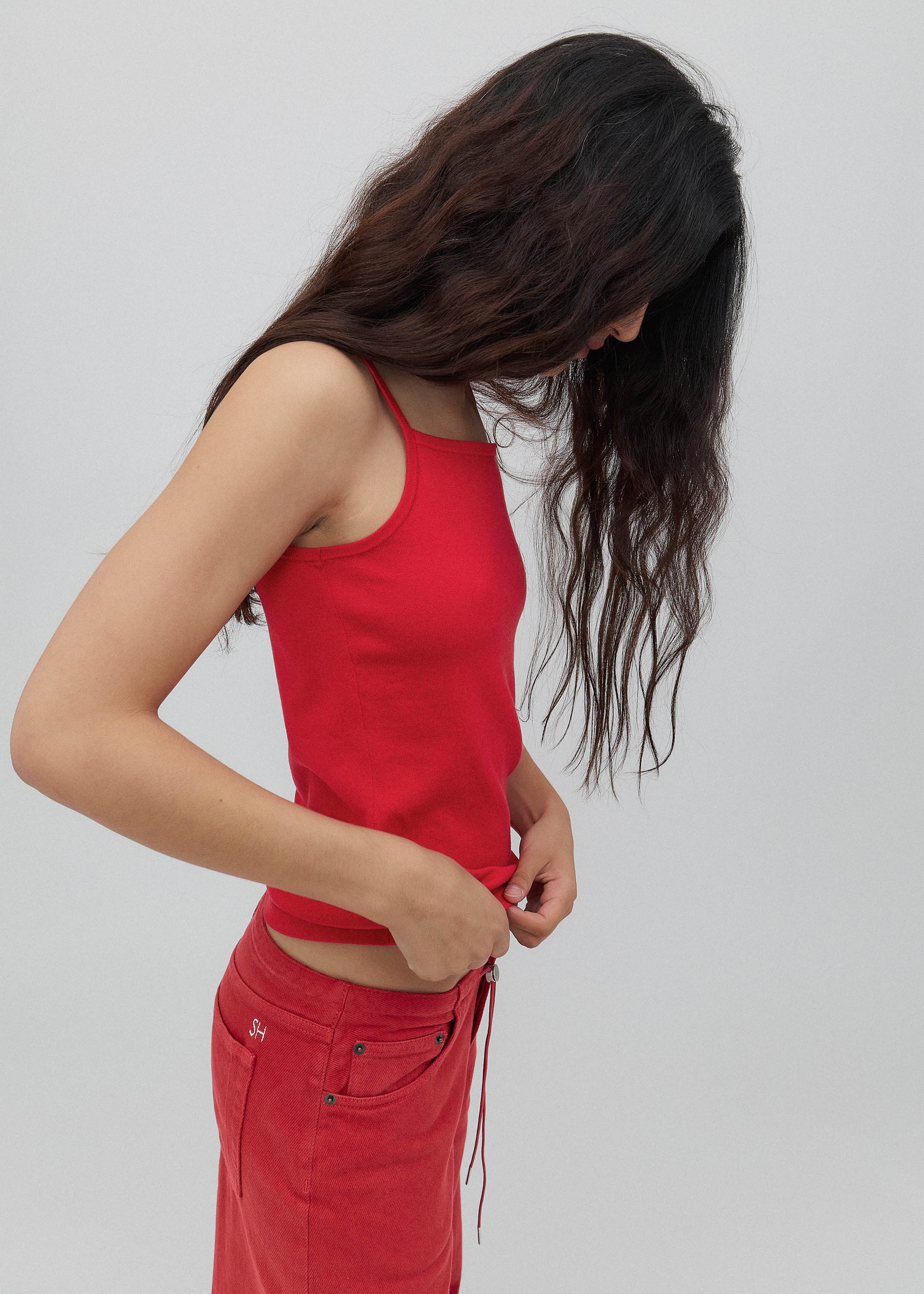 Person wearing a red tank top and red pants against a plain background