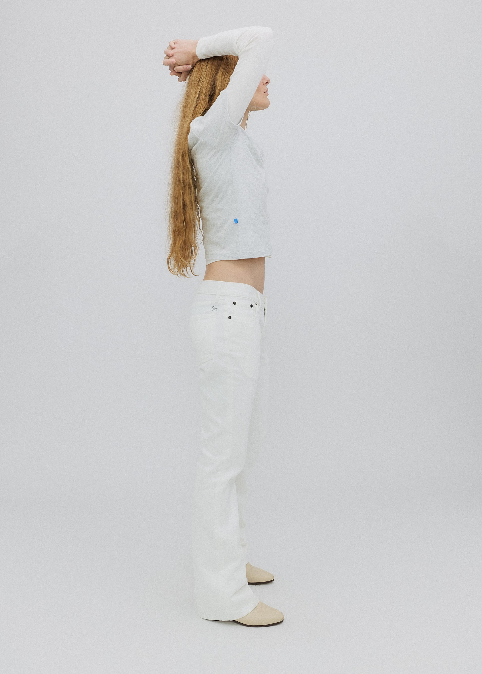 Person wearing a white long-sleeve top and pants on a plain background