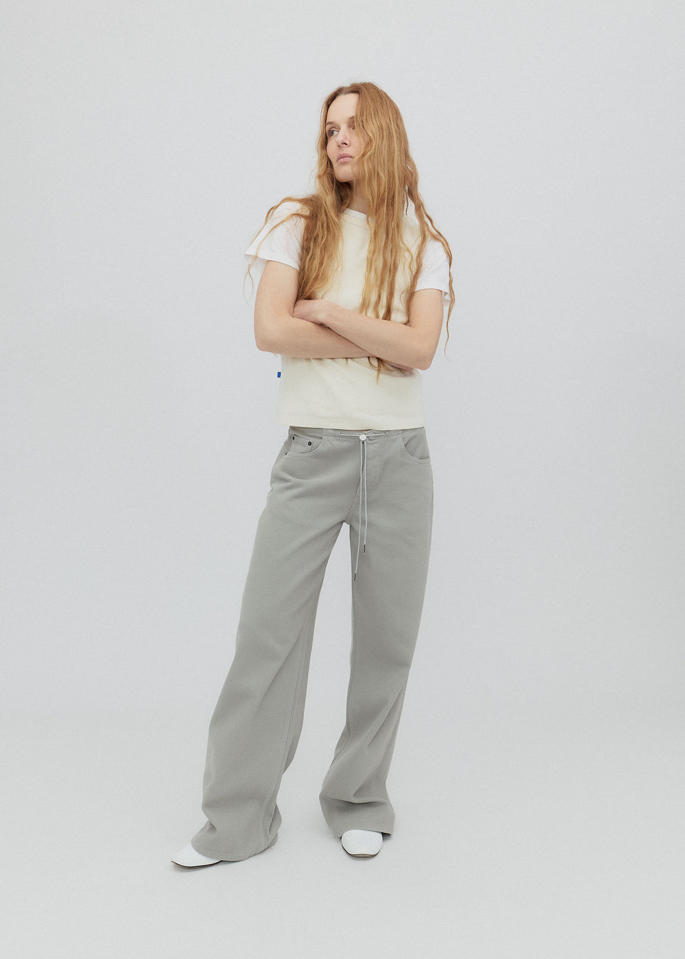 Person wearing a white top and gray pants on a light gray background