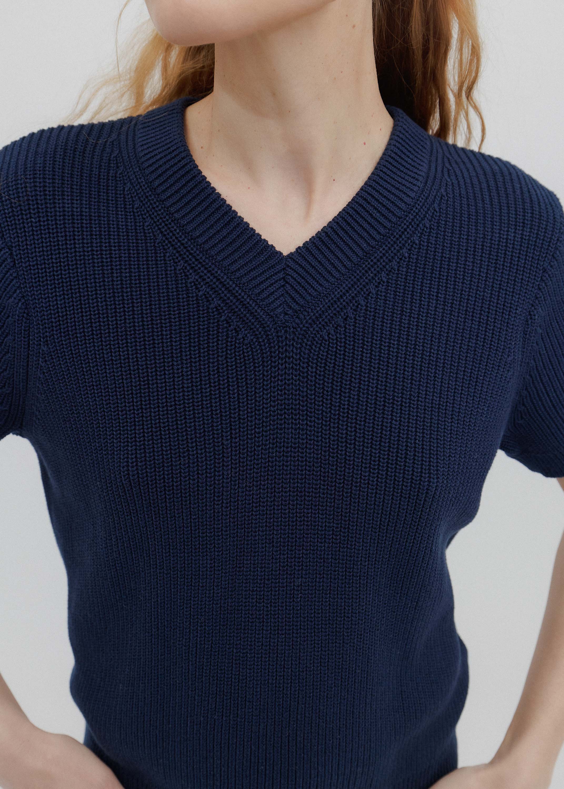Navy blue short-sleeve sweater worn by a person on a light gray background