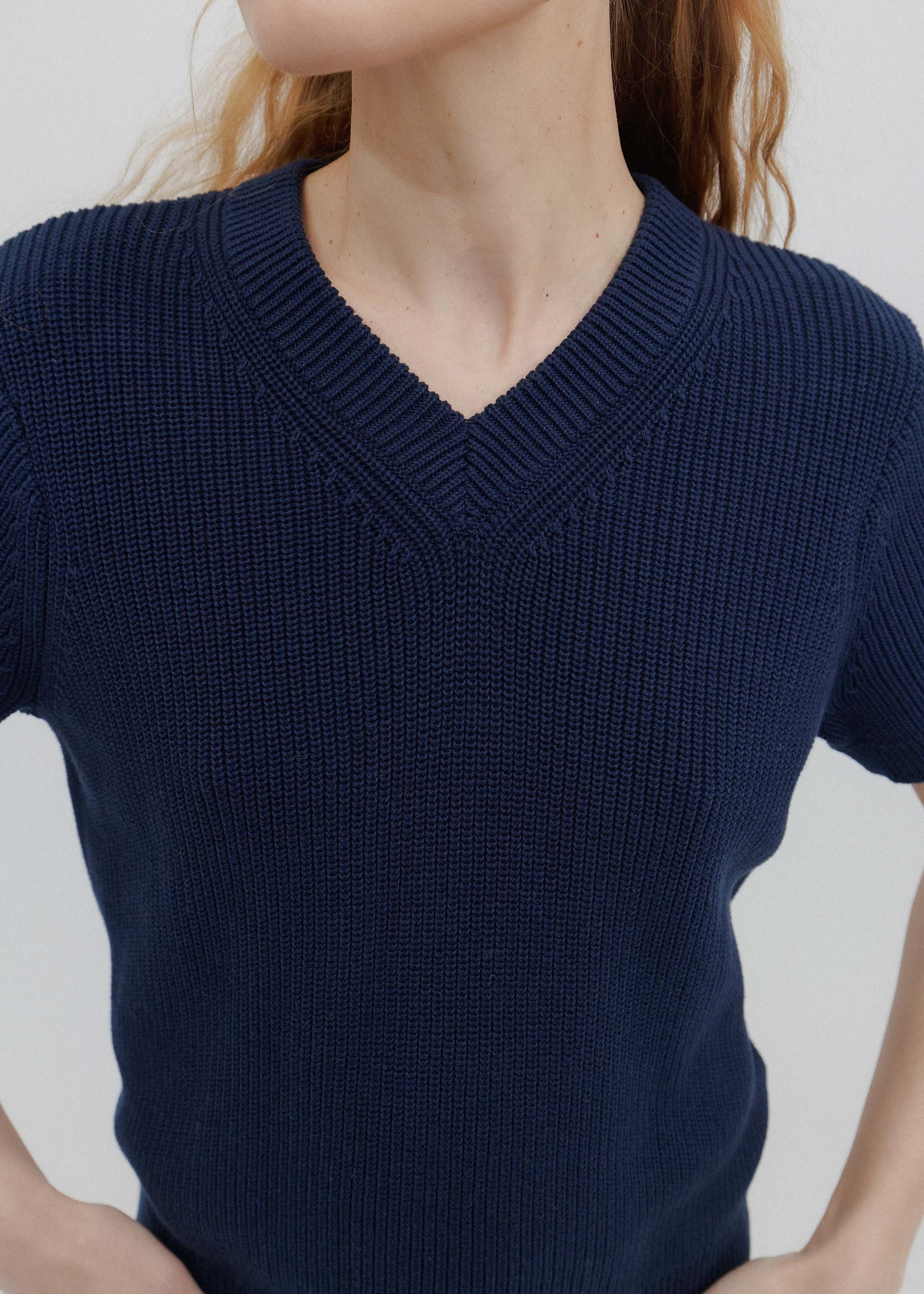 Navy blue short-sleeve sweater worn by a person on a light gray background