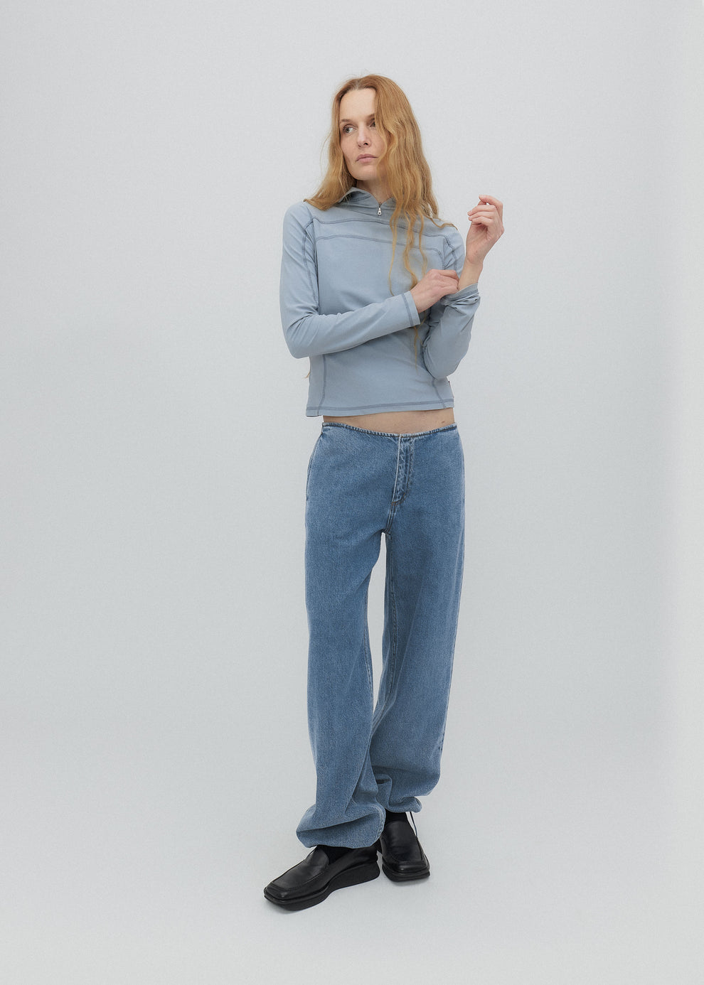 Woman wearing a light blue sweater and jeans on a white background