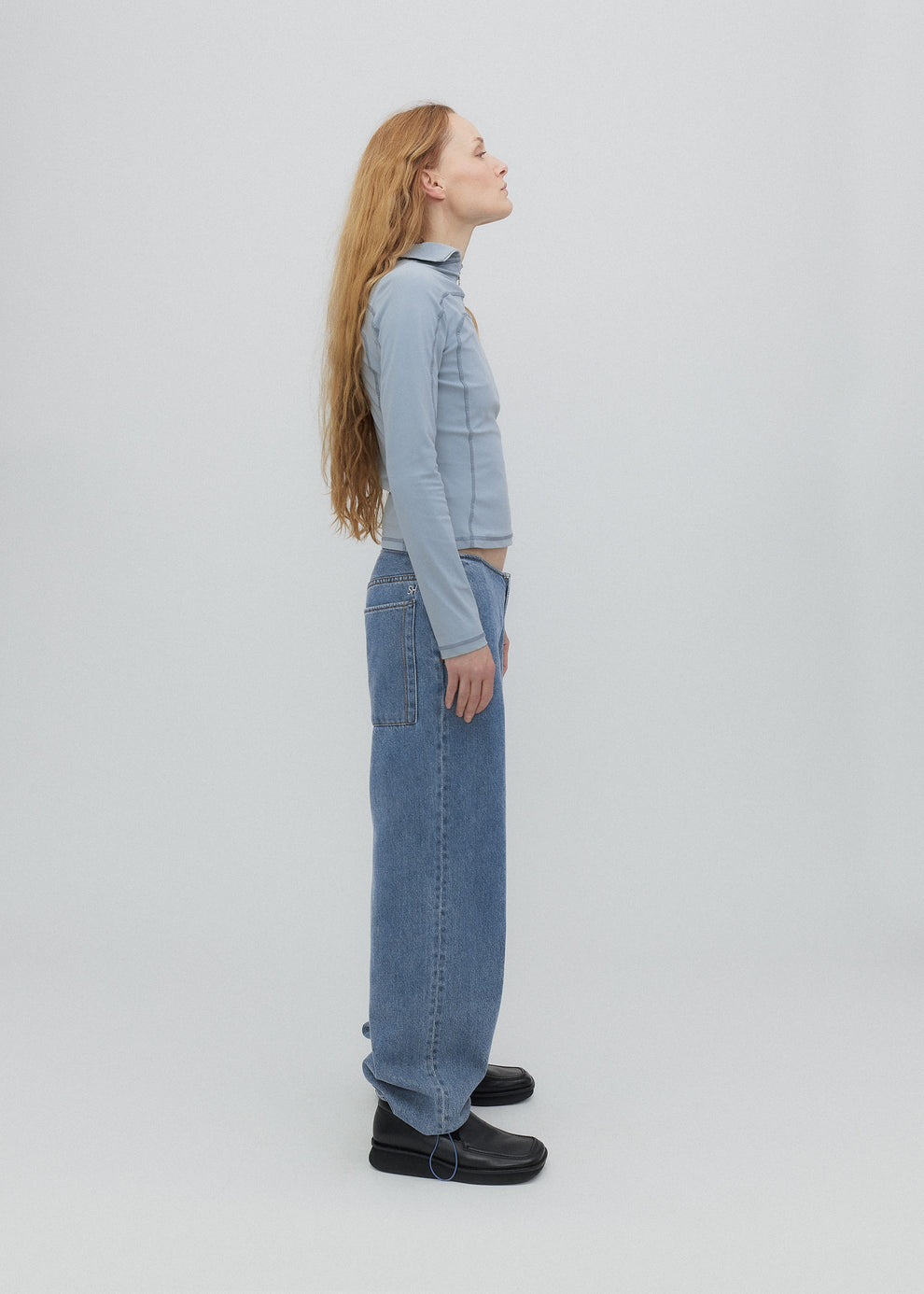 Person wearing a light blue denim outfit on a white background