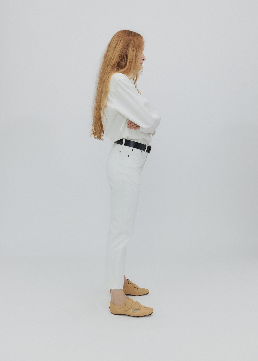 Person wearing a white outfit with beige shoes on a plain background