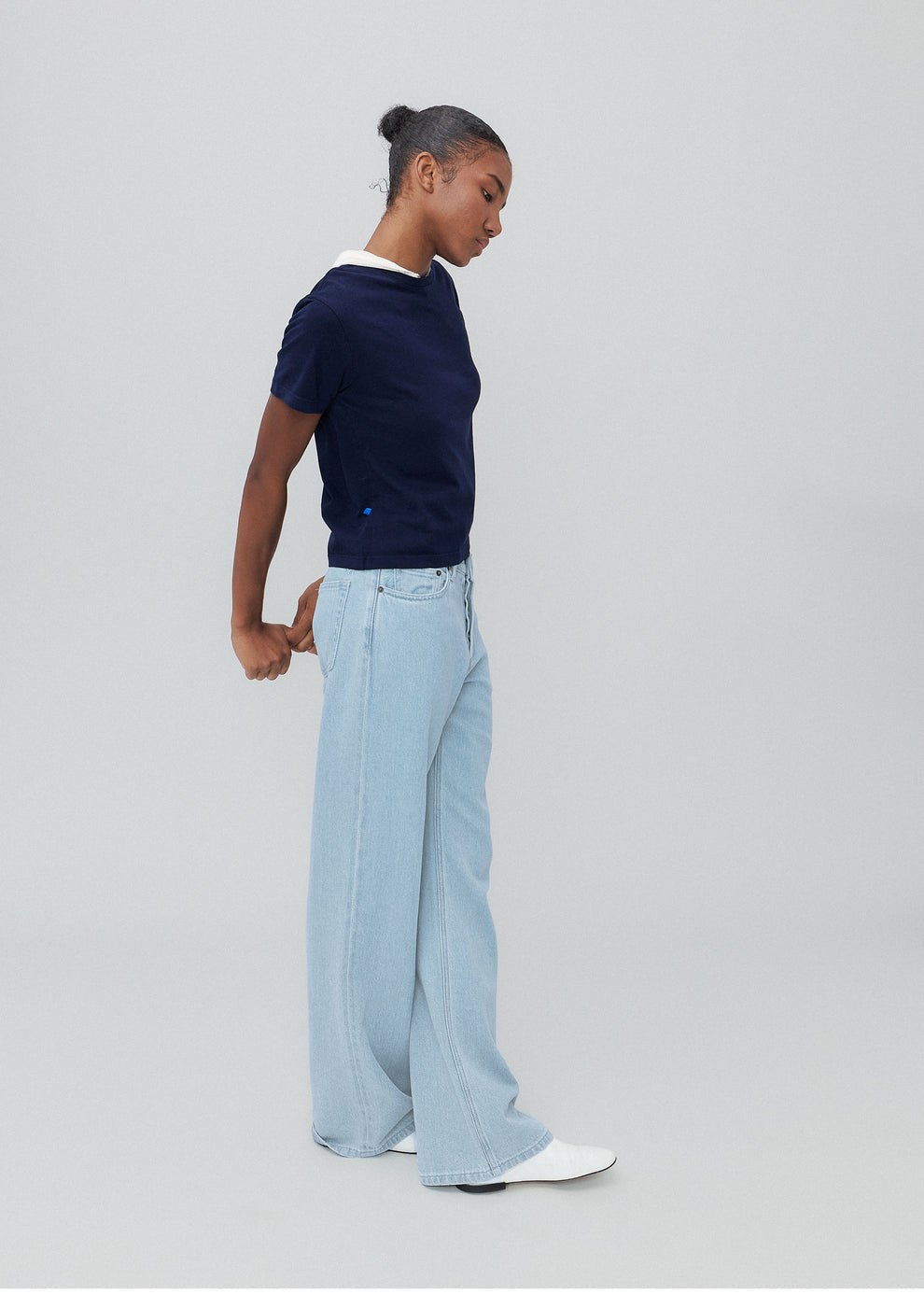 Person wearing a navy t-shirt and light blue pants on a gray background