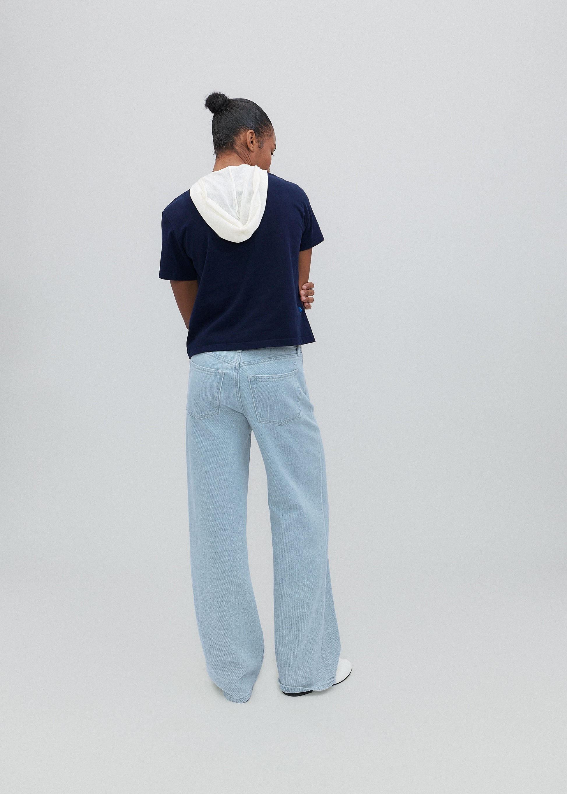 Person wearing a navy t-shirt and light blue jeans against a plain background
