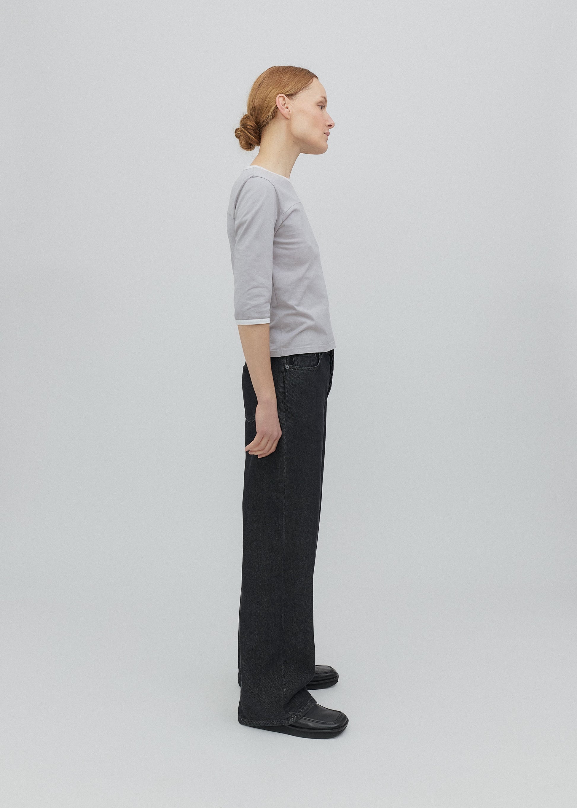 Person wearing a gray shirt and black pants on a light gray background