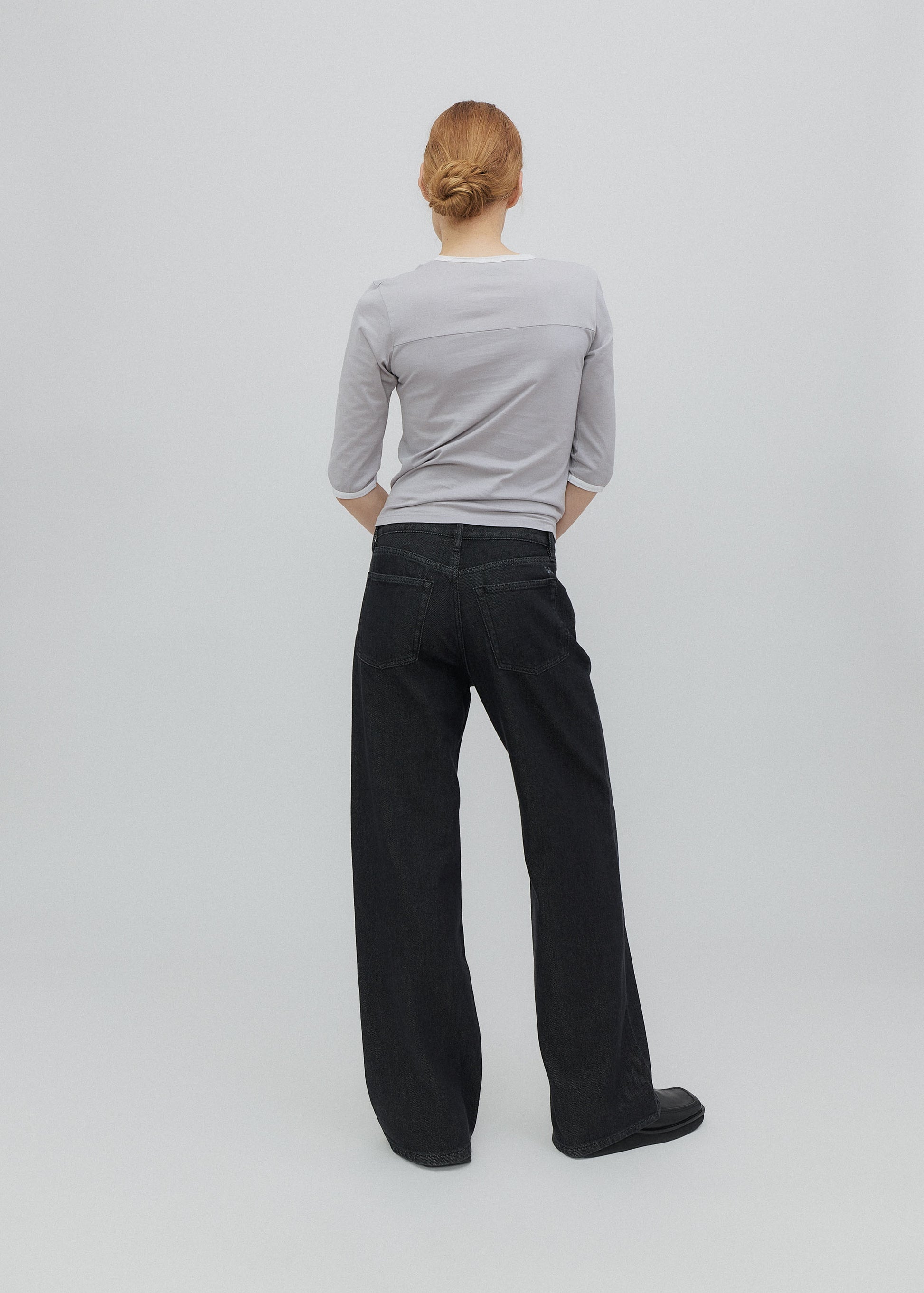 Person wearing a gray shirt and black pants on a white background