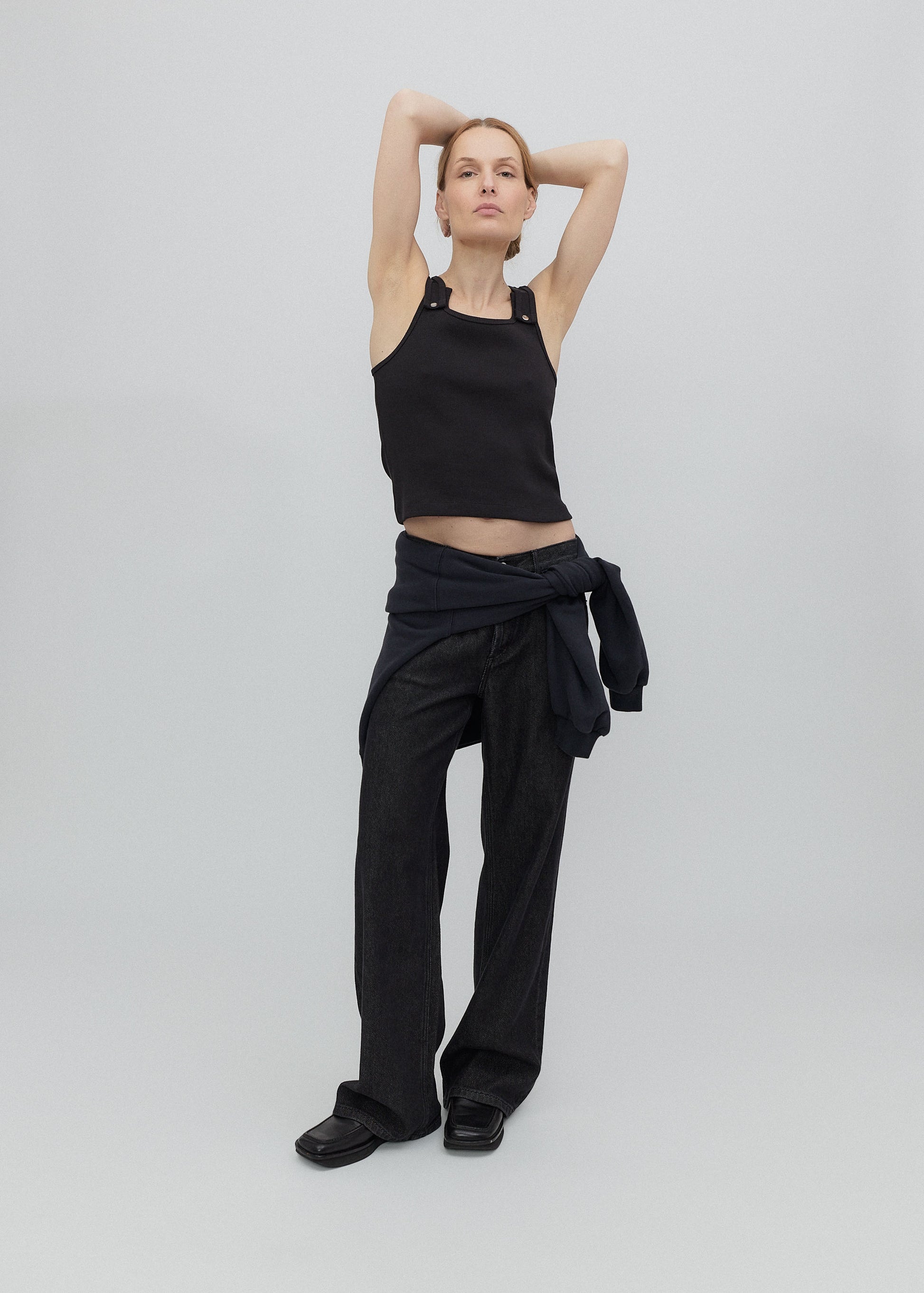 Person wearing a black outfit with a top and pants on a plain background