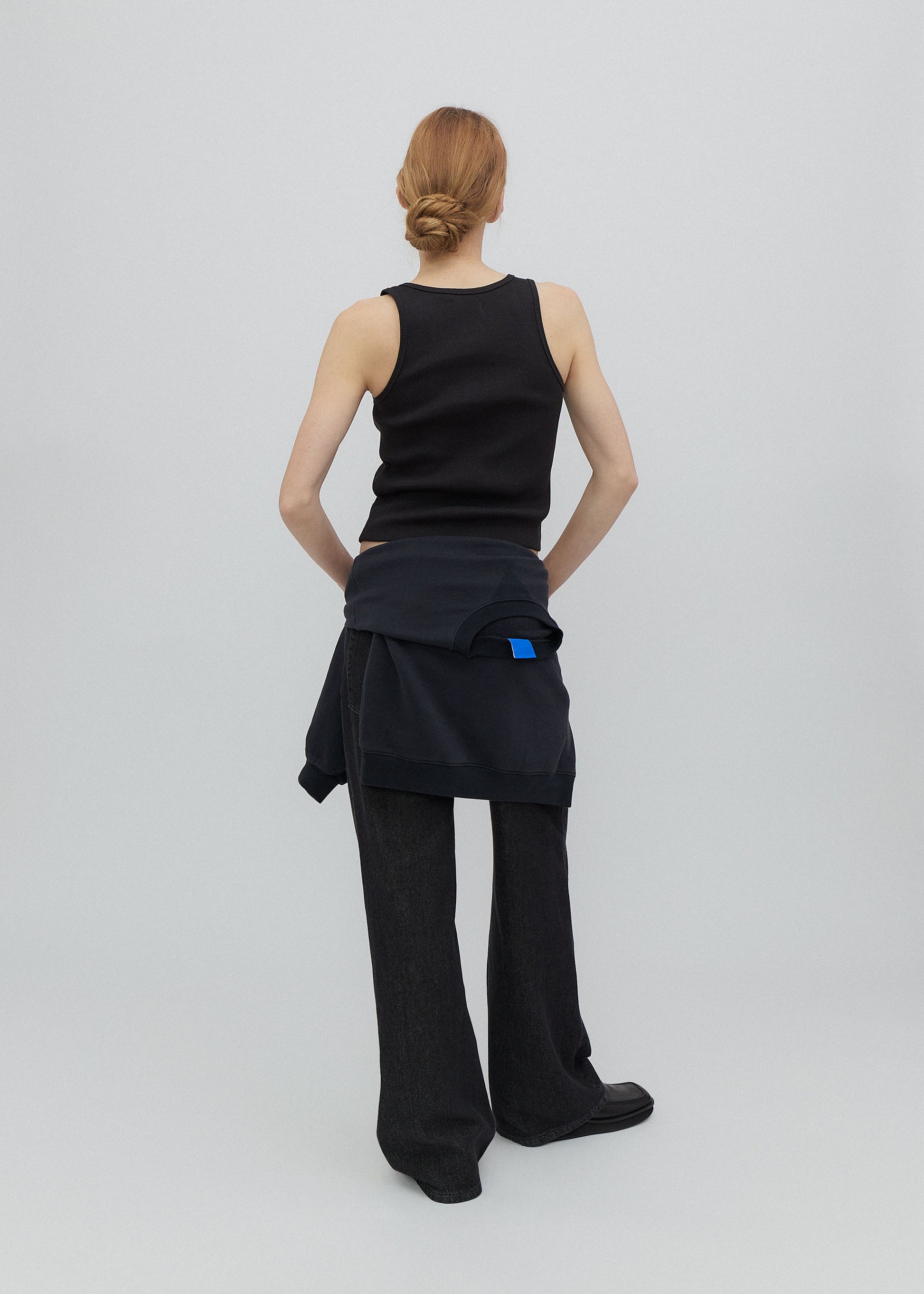 Person wearing a black sleeveless top and wide-leg pants on a light gray background