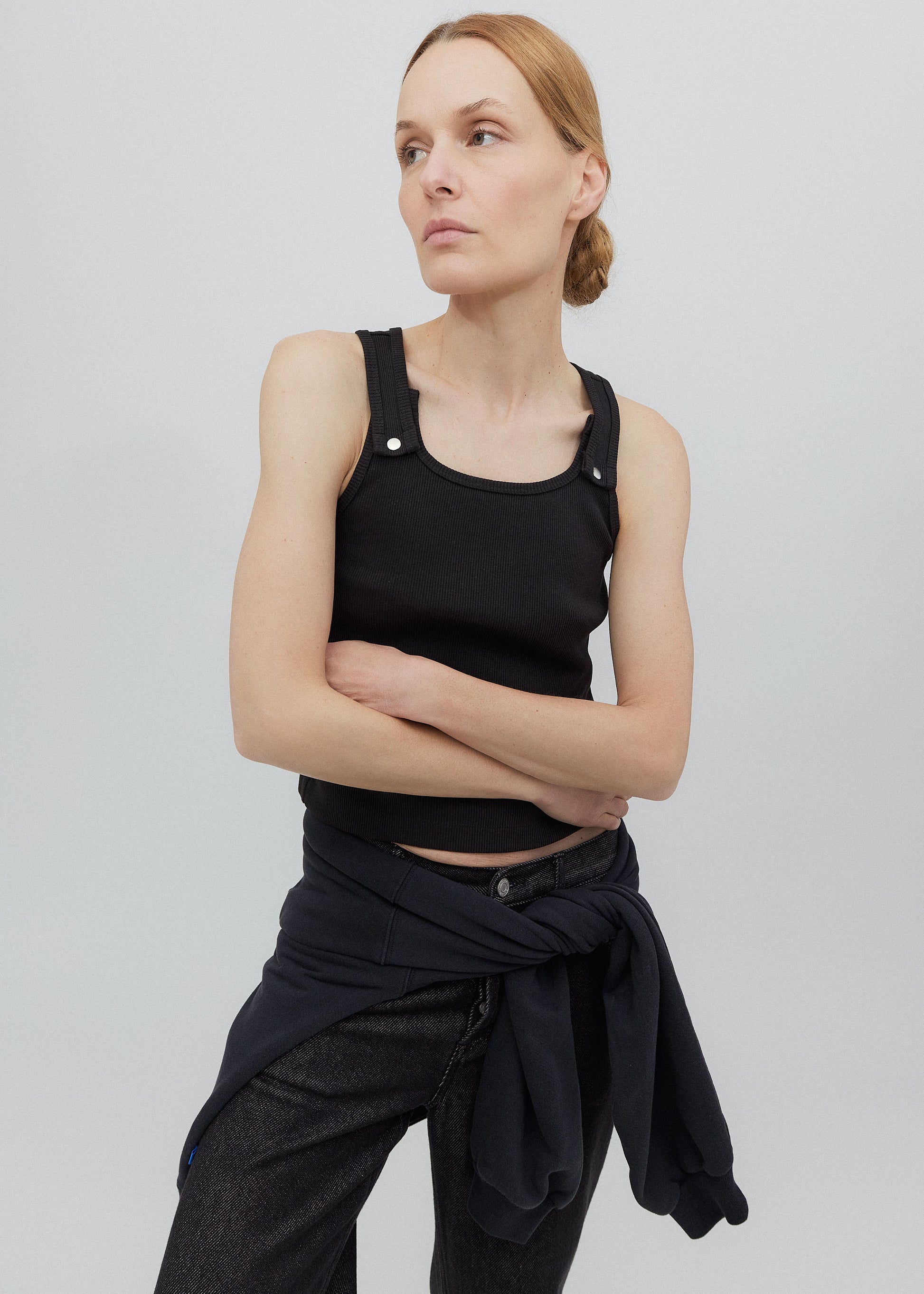 Woman wearing a black sleeveless top and pants against a plain background