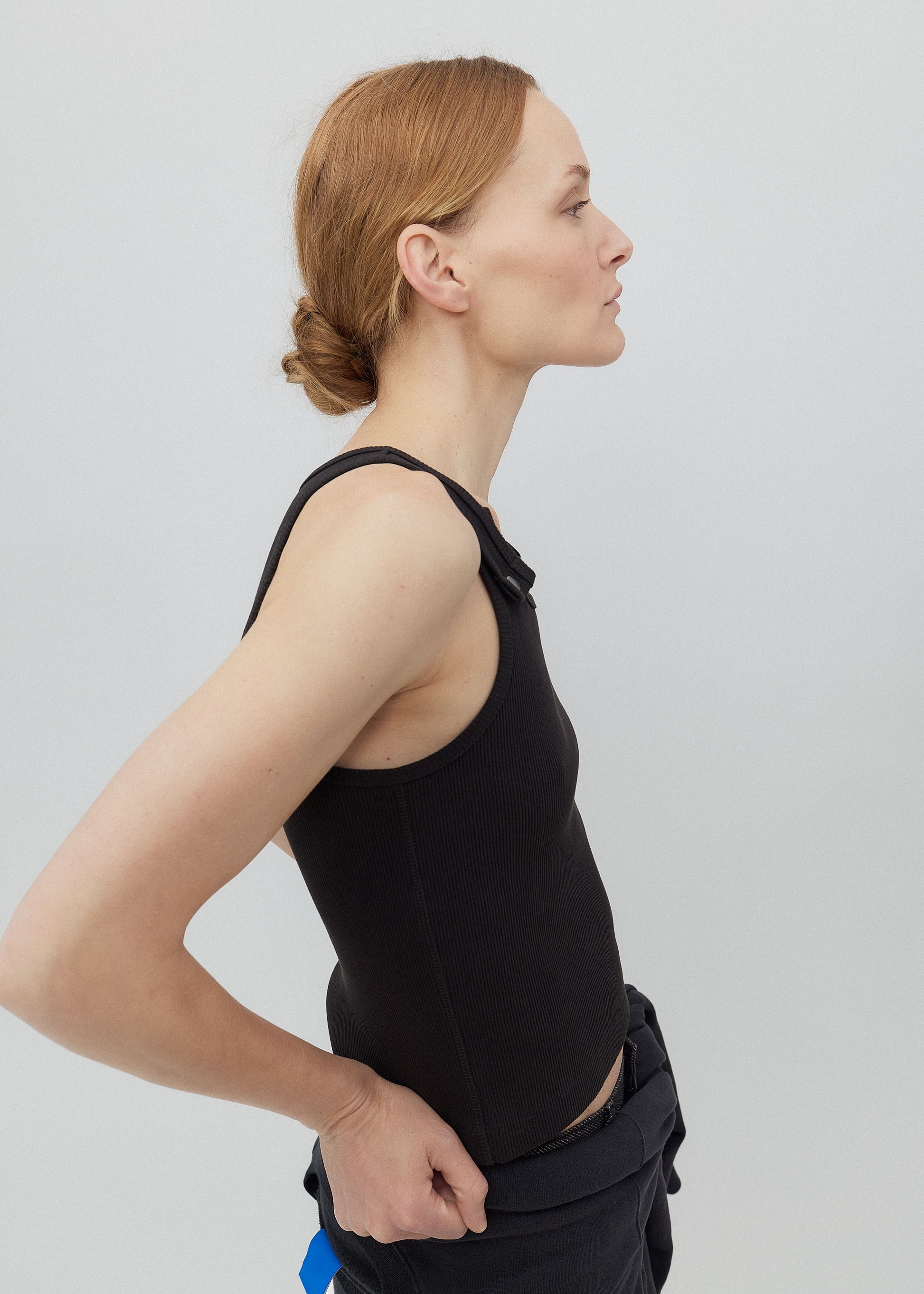 Woman wearing a black sleeveless top against a plain background