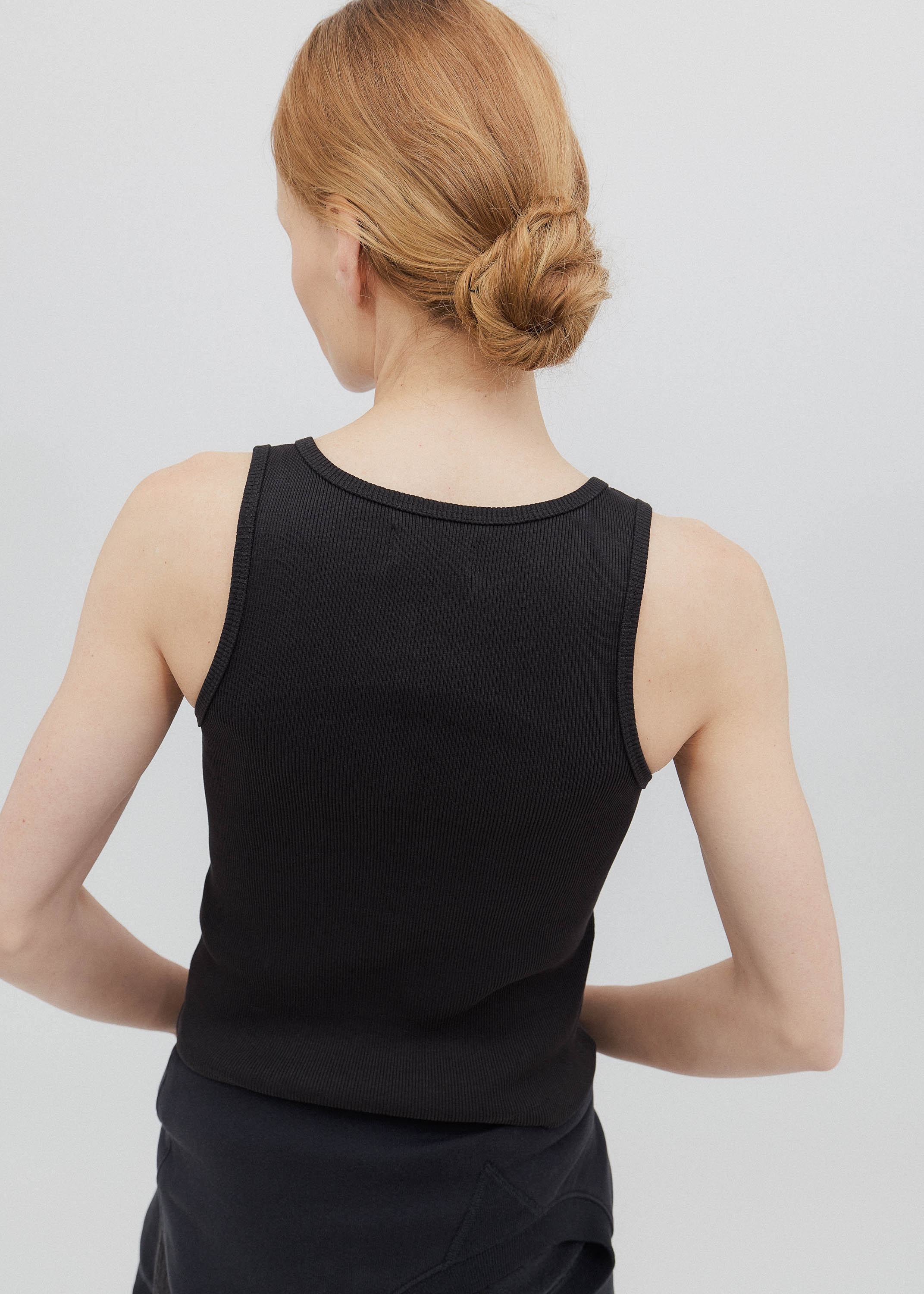 Person wearing a black sleeveless top against a plain background