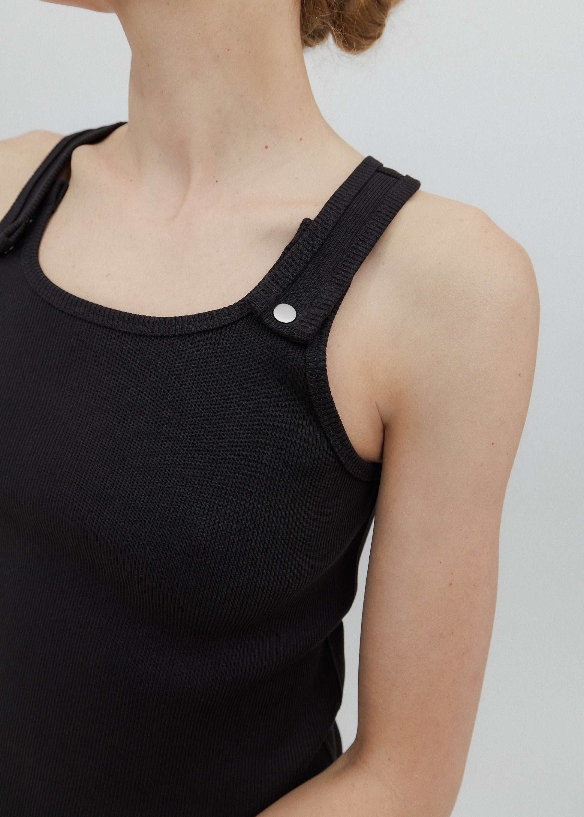 Black tank top with thin straps on a plain background